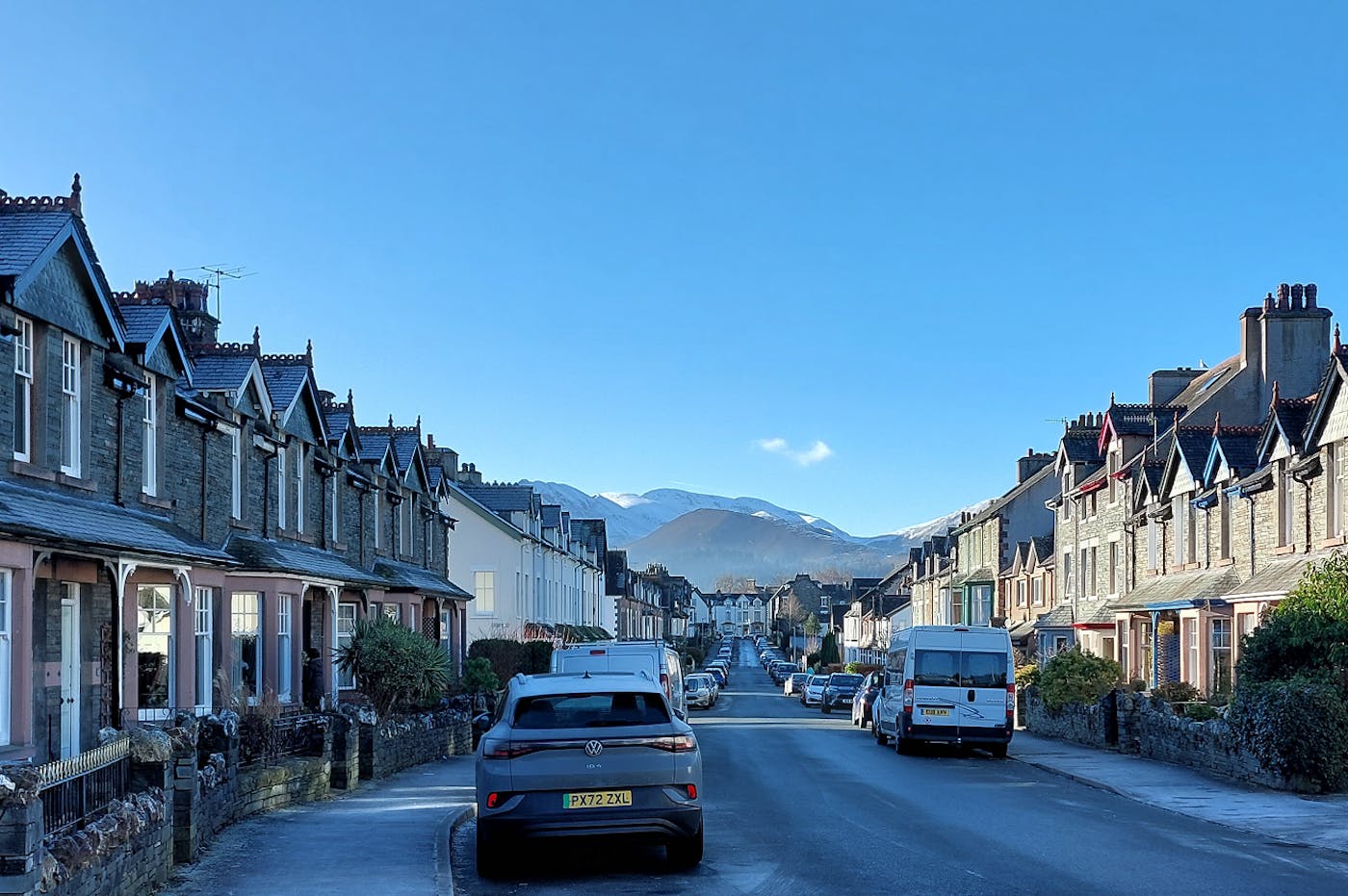 A road with houses either side and mountains in the distance