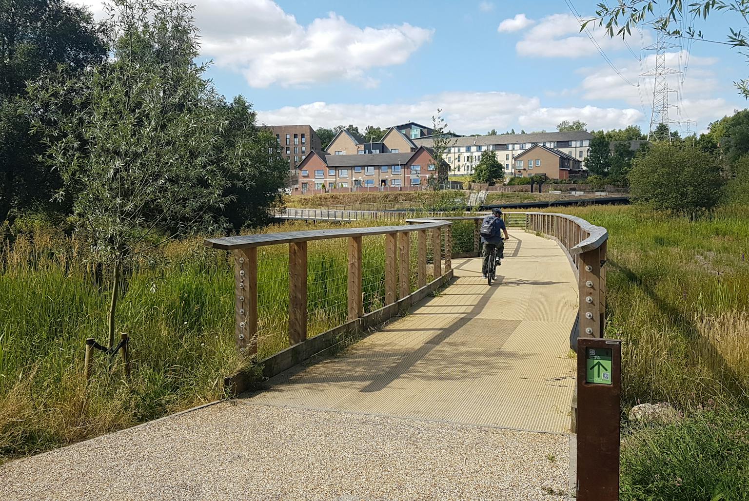 A man on a bike riding over a bridge towards some houses