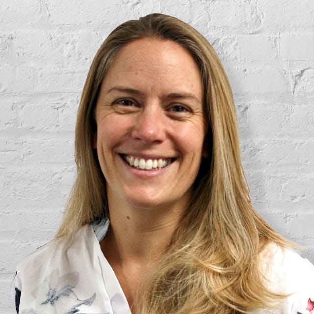 Person smiling in front of brick wall