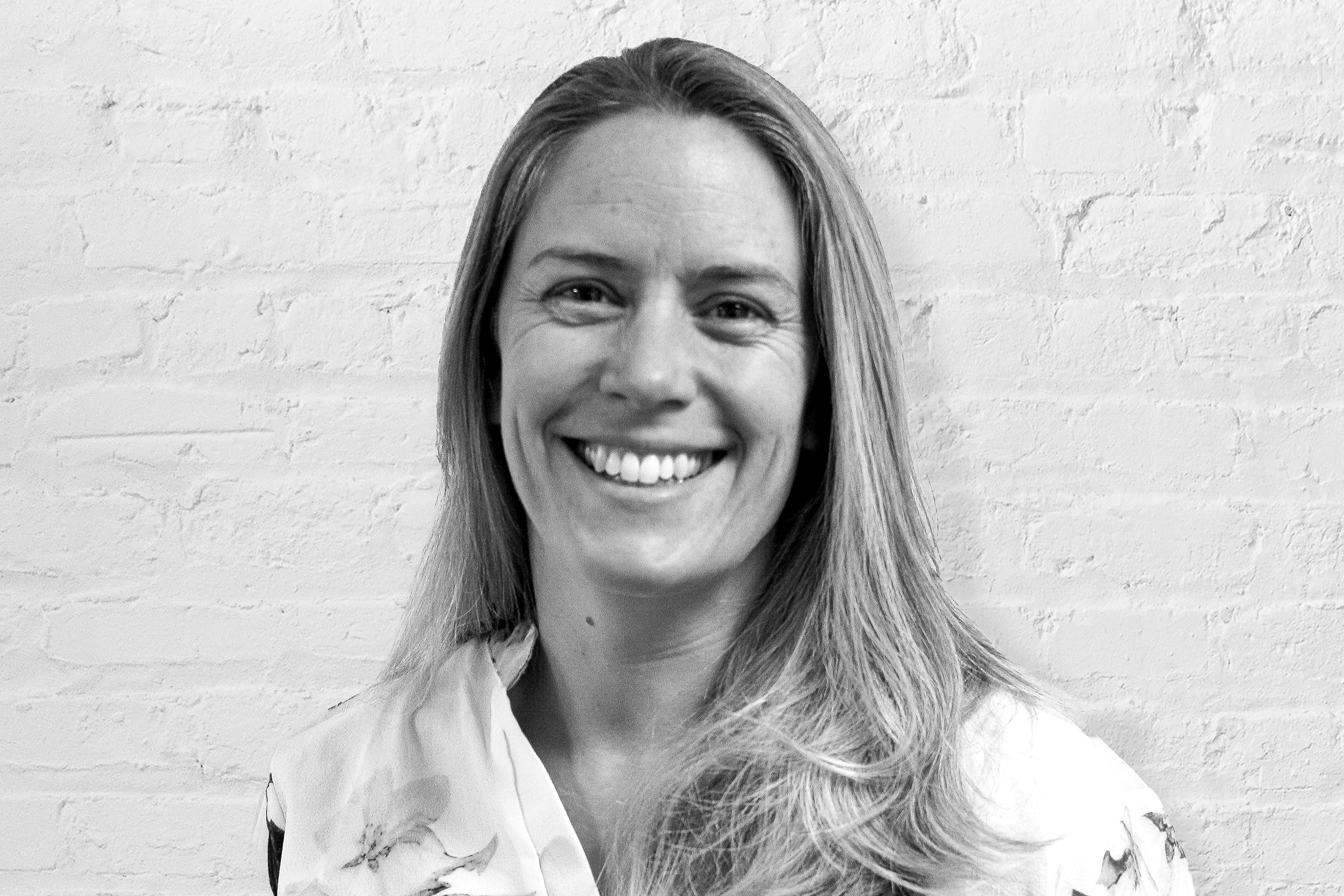 Person smiling in front of brick wall