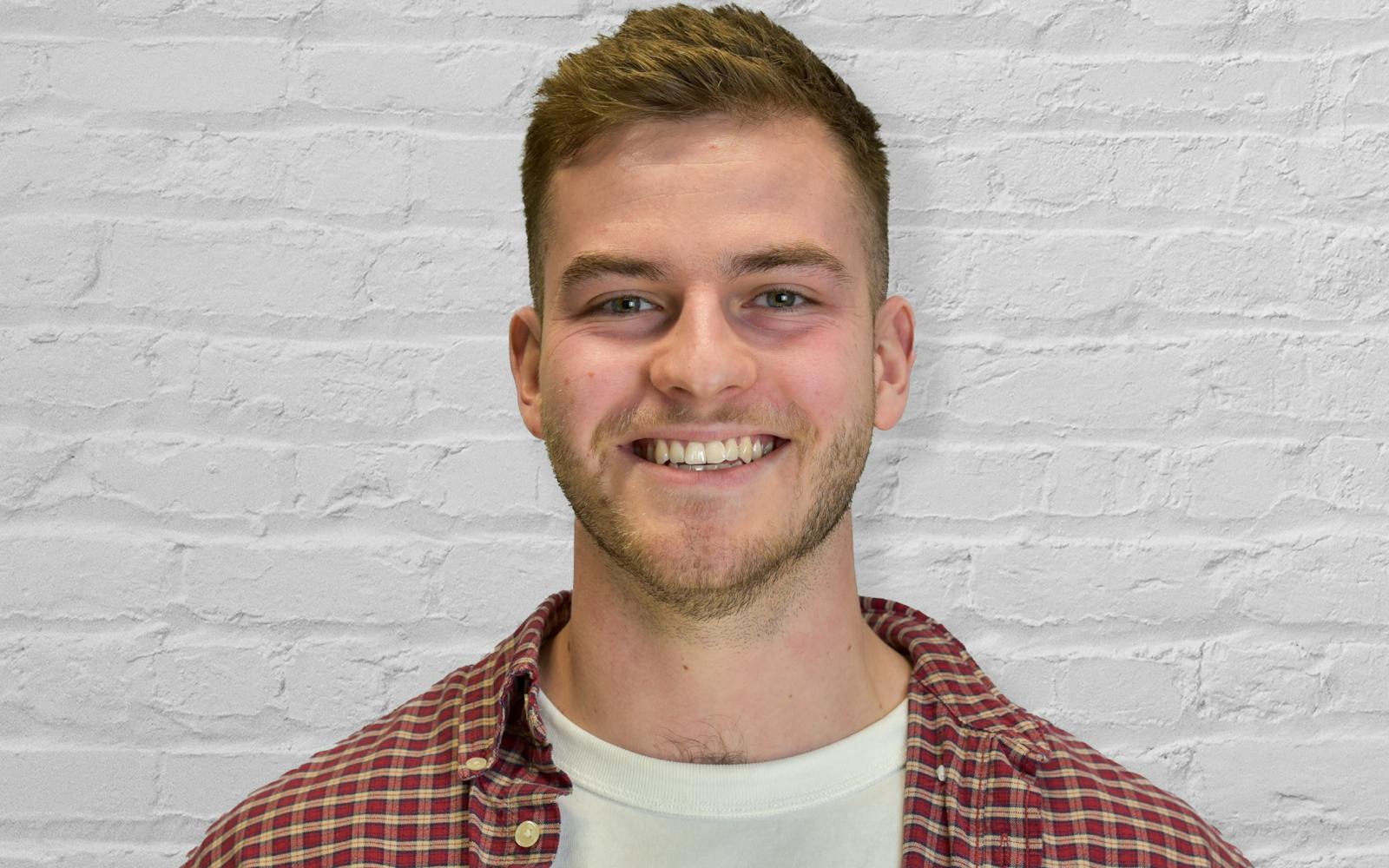 person smiling in front of brick wall