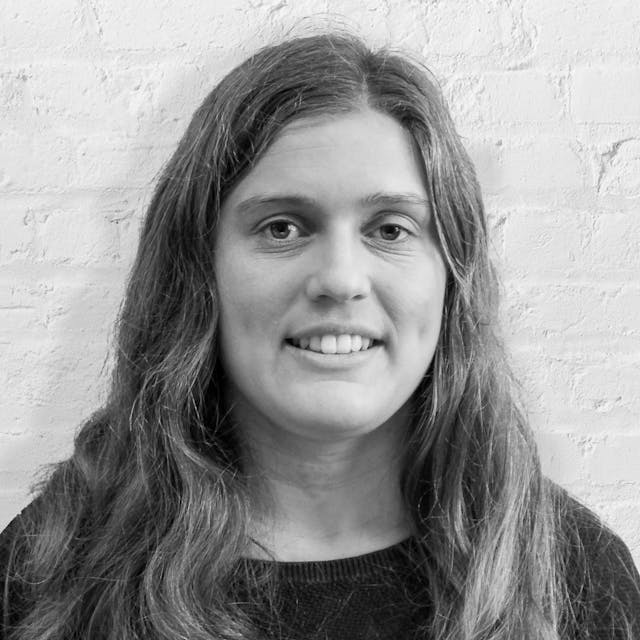 Person smiling in front of white brick wall
