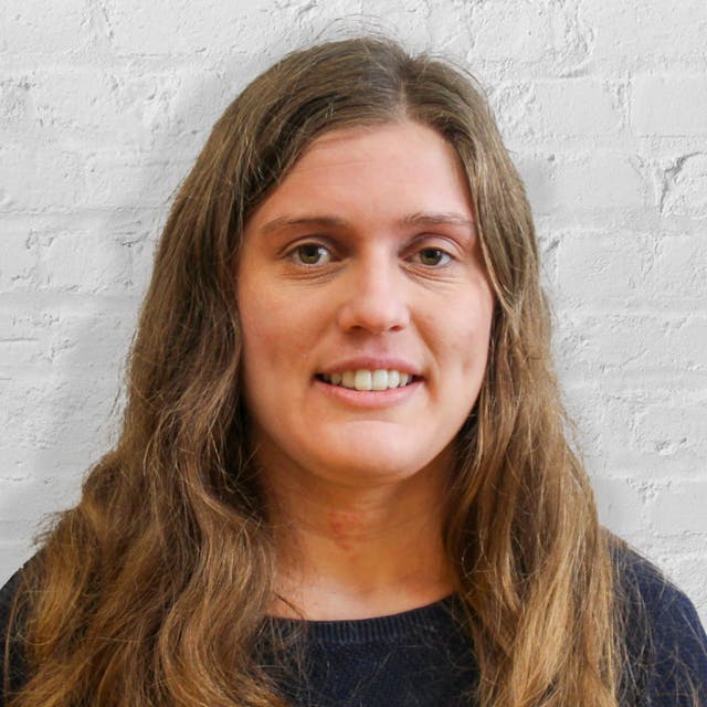 Person smiling in front of white brick wall