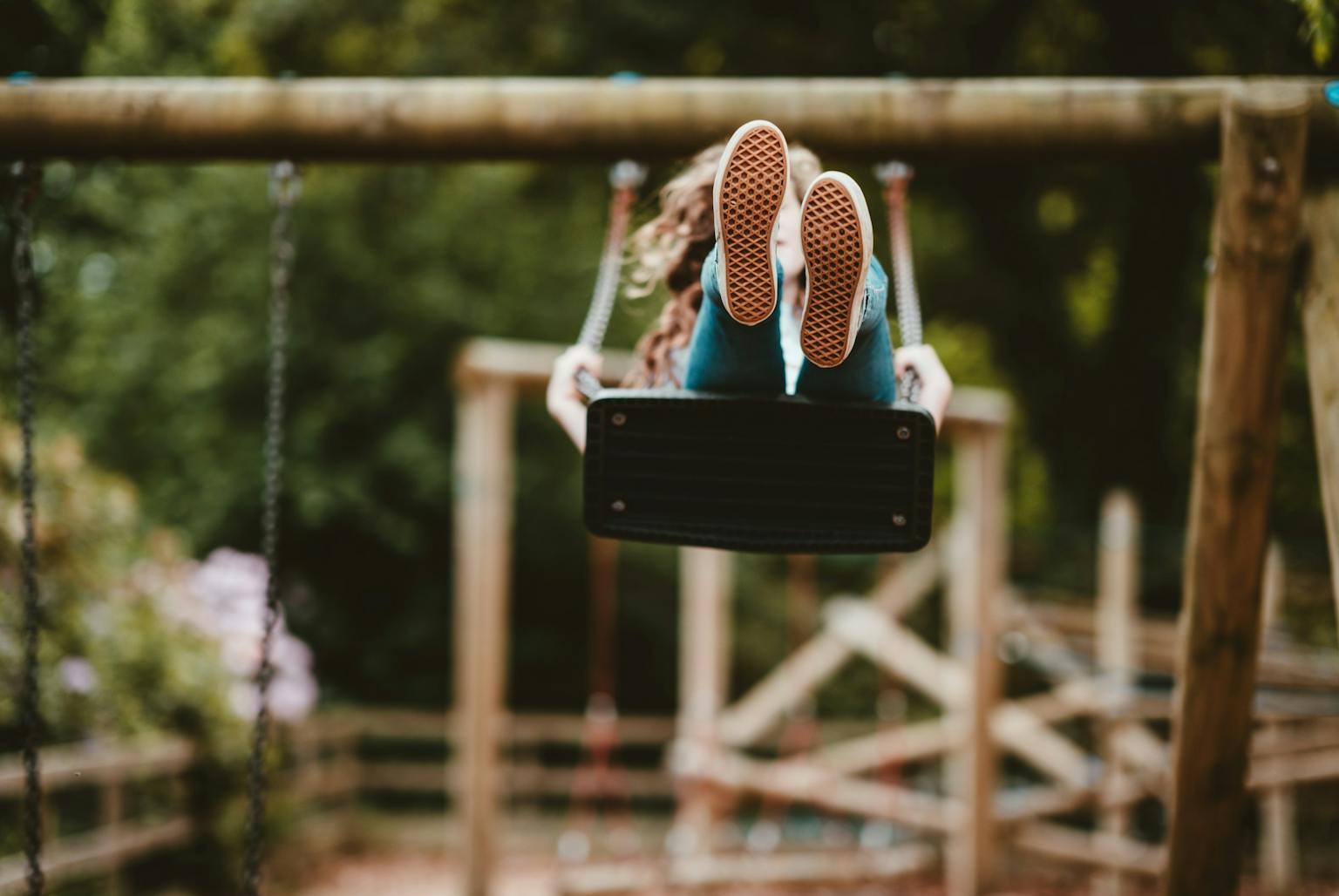 Child swinging on a swing in wooden play area