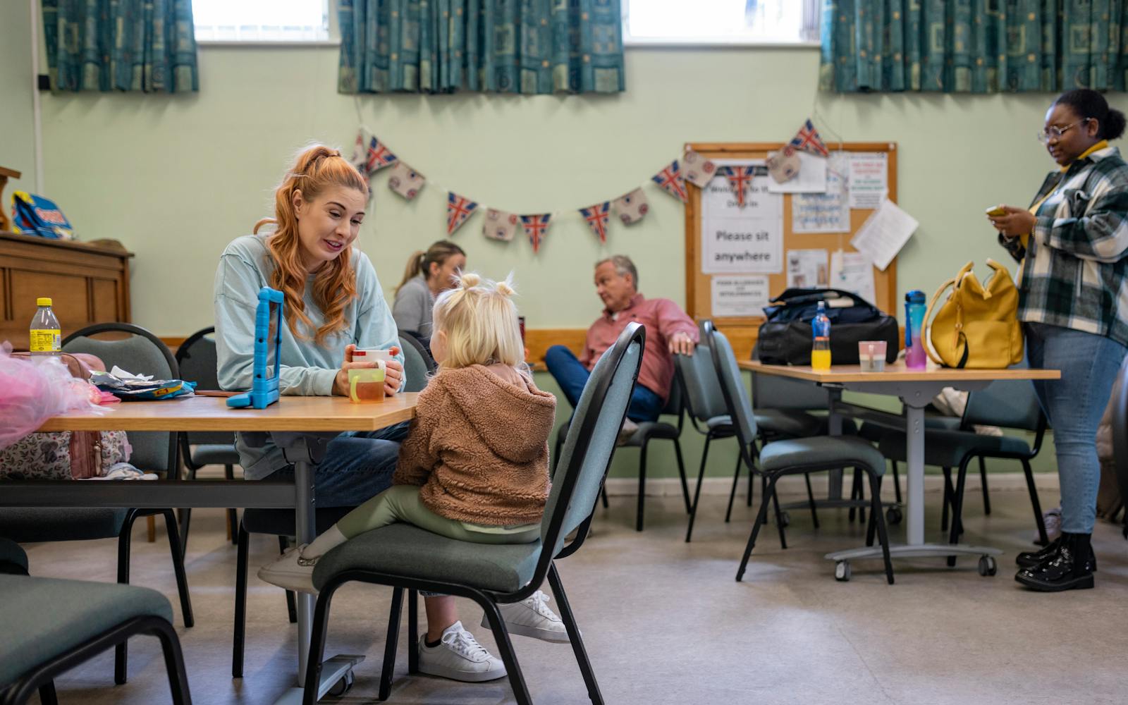 A woman and two children sitting at a table in a room, engaged in conversation and enjoying a snack together.