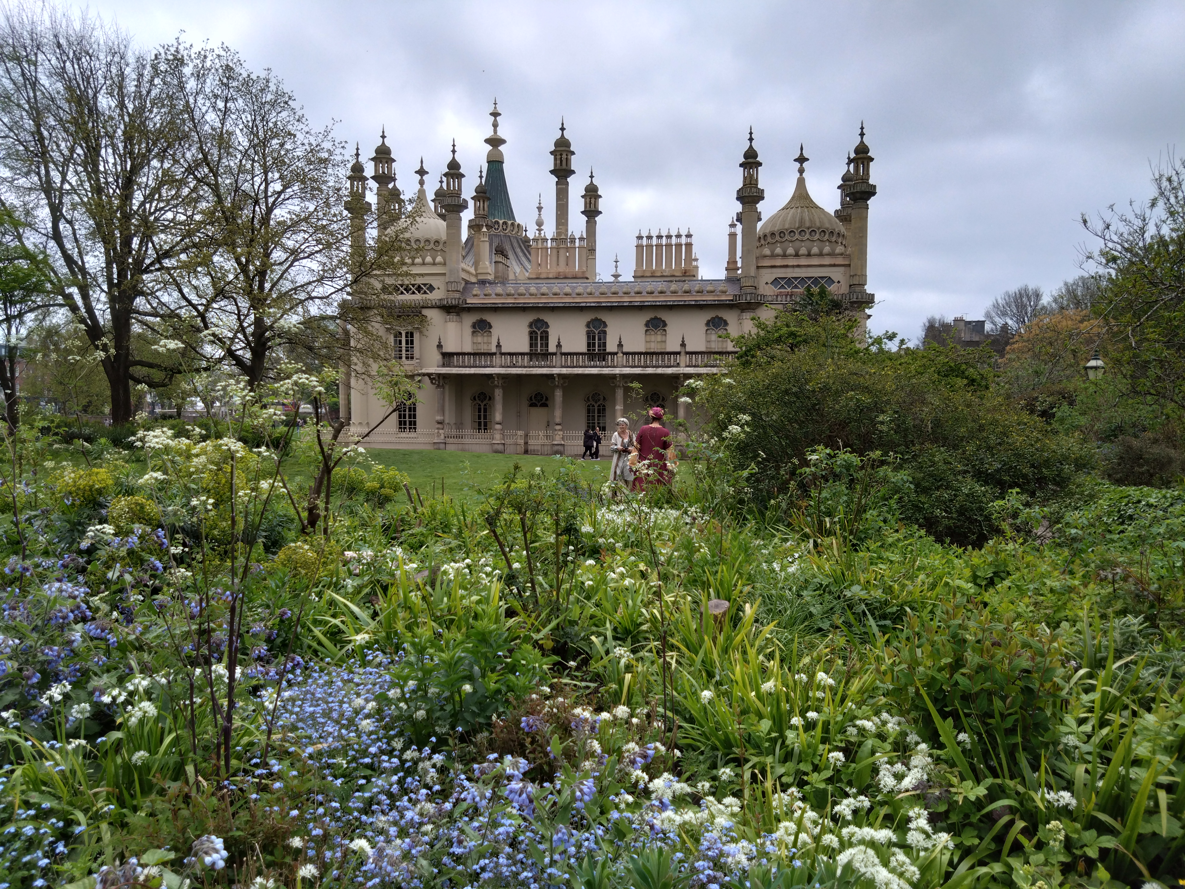 a building with towers and spires in front of a garden