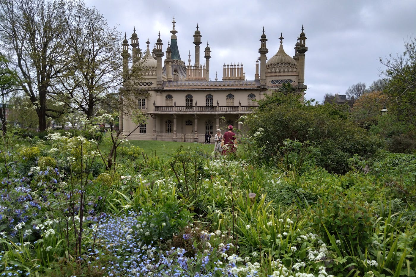 a building with towers and spires in front of a garden