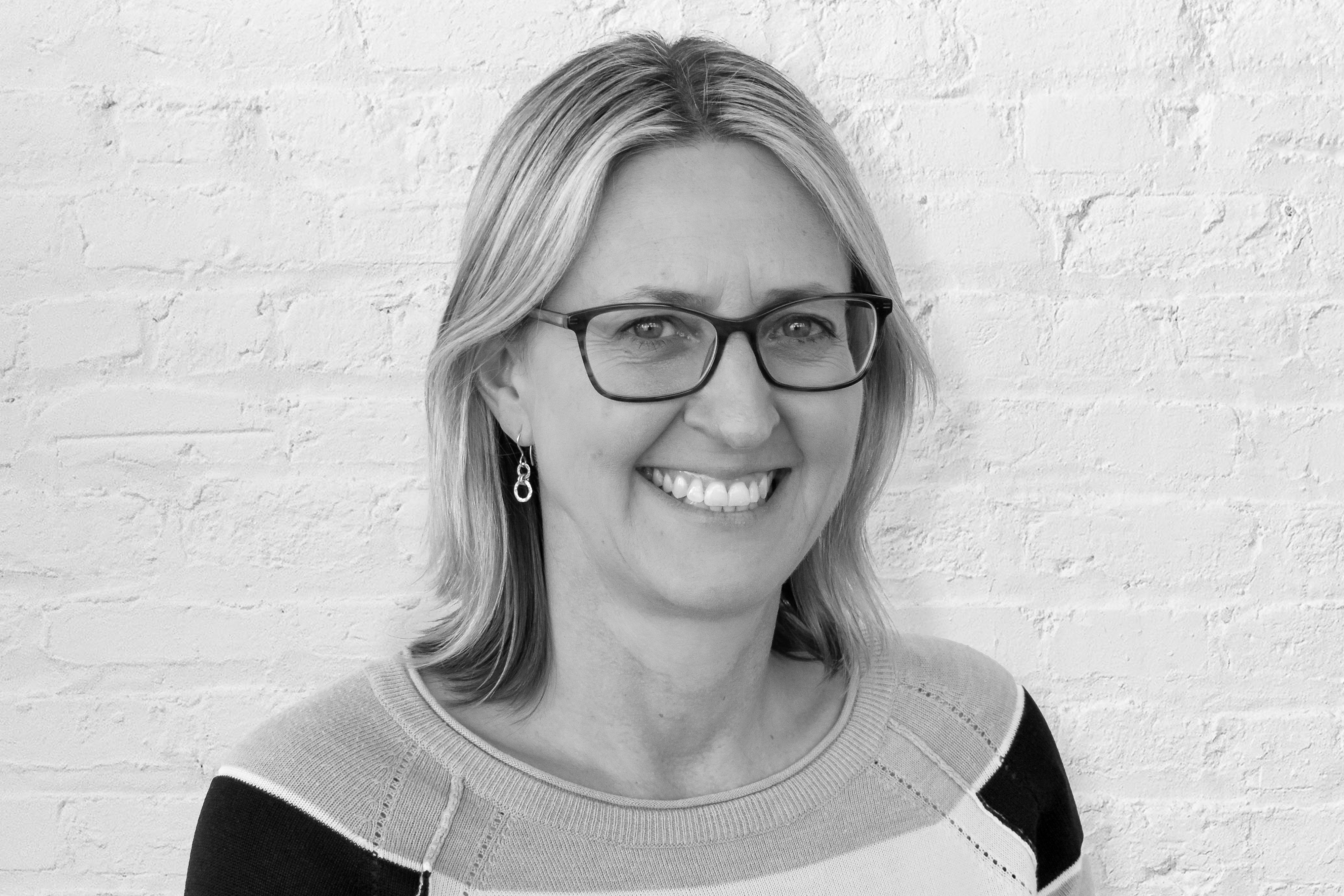 Taran Livingston smiling in front of a white brick wall