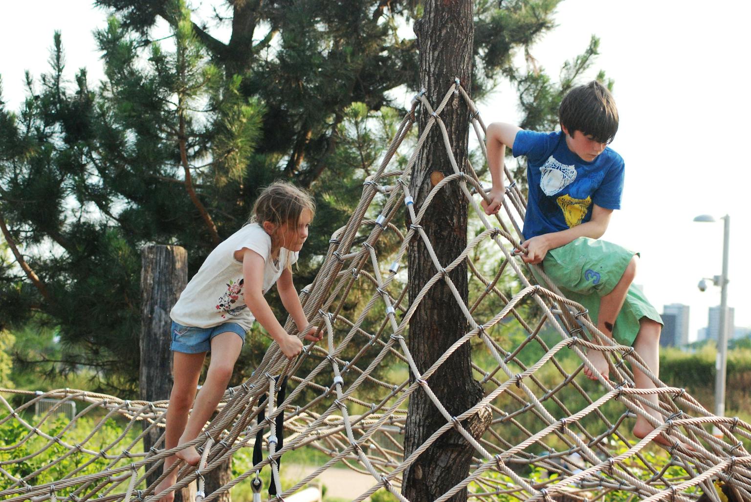 a boy and girl climbing on ropes