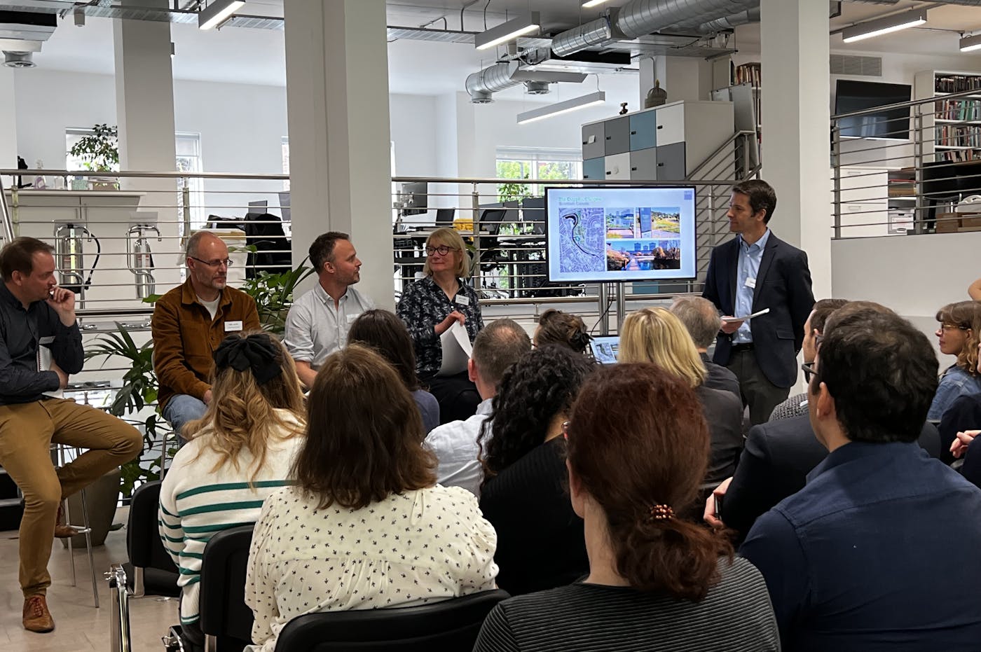 Crowd of people watching a panel discussion comprisng five people