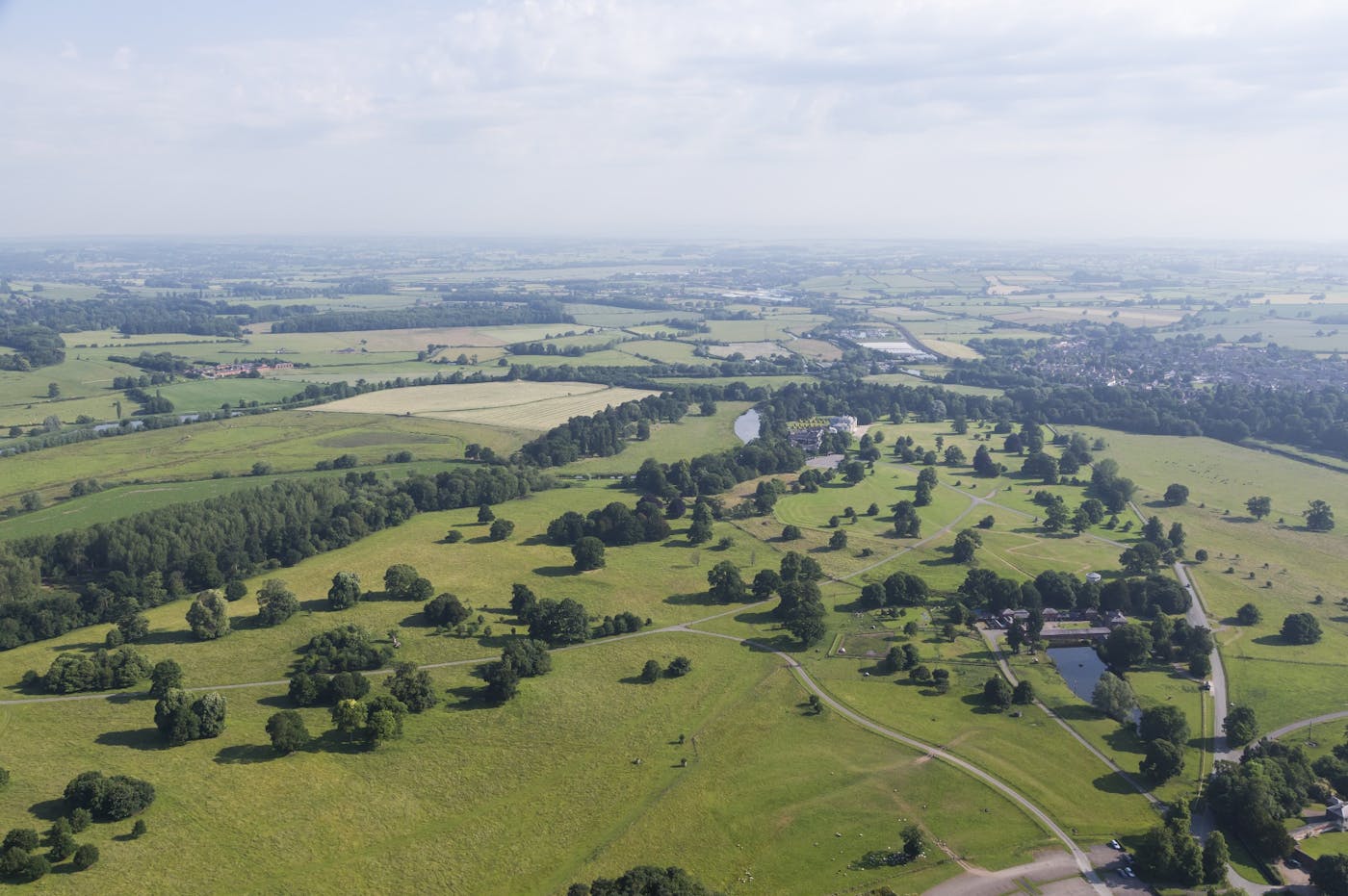 Aerial photo of green flat landscape with trees, roads and patches of water