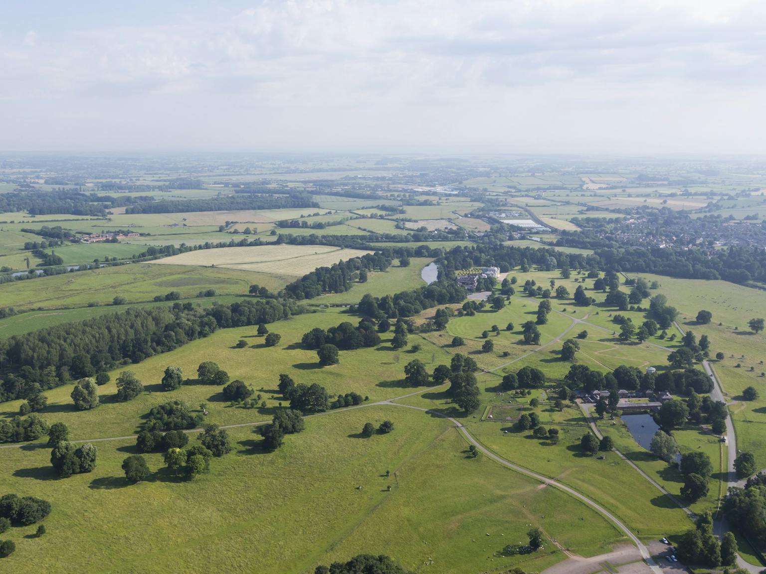 Aerial photo of green flat landscape with trees, roads and patches of water