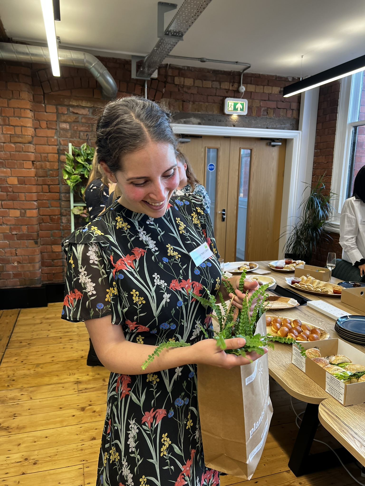 A person smiling at a houseplant giftbag 