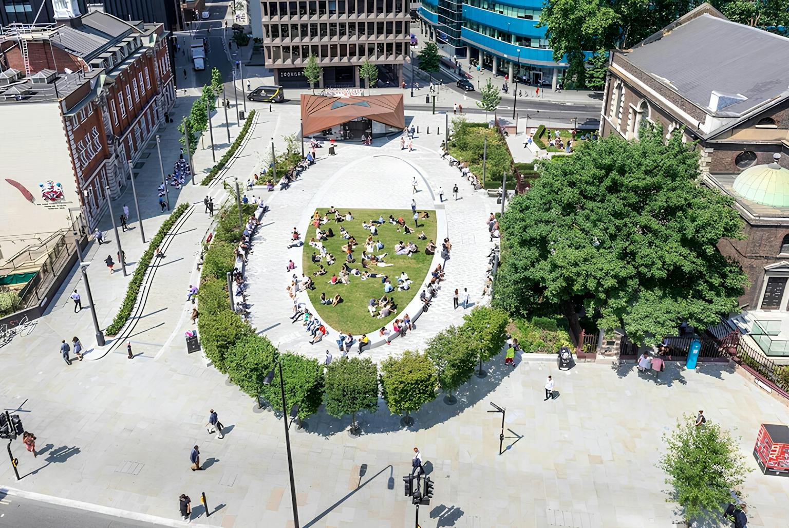 Aerial photograph of a rectangular urban park with a central oval lawn filled with people, surrounded by paved walkways, trees, and buildings.