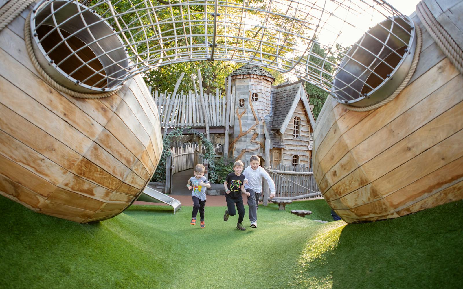 Three children running underneath a wood and metal construction in a playground