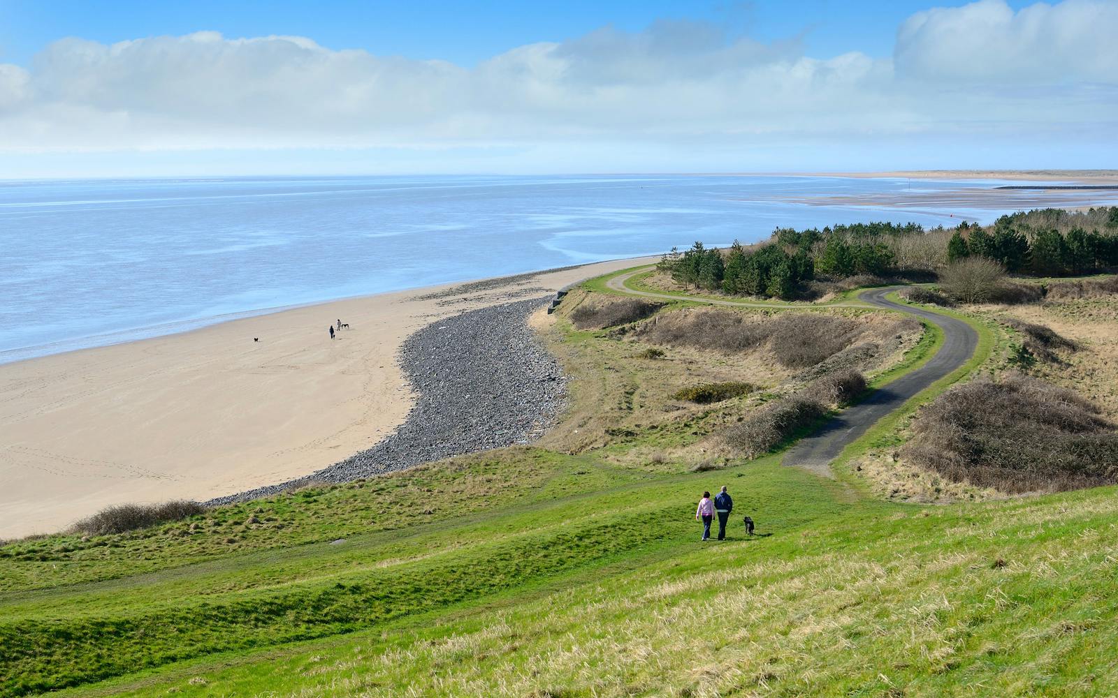 A beach with blue skies and green fields nearby