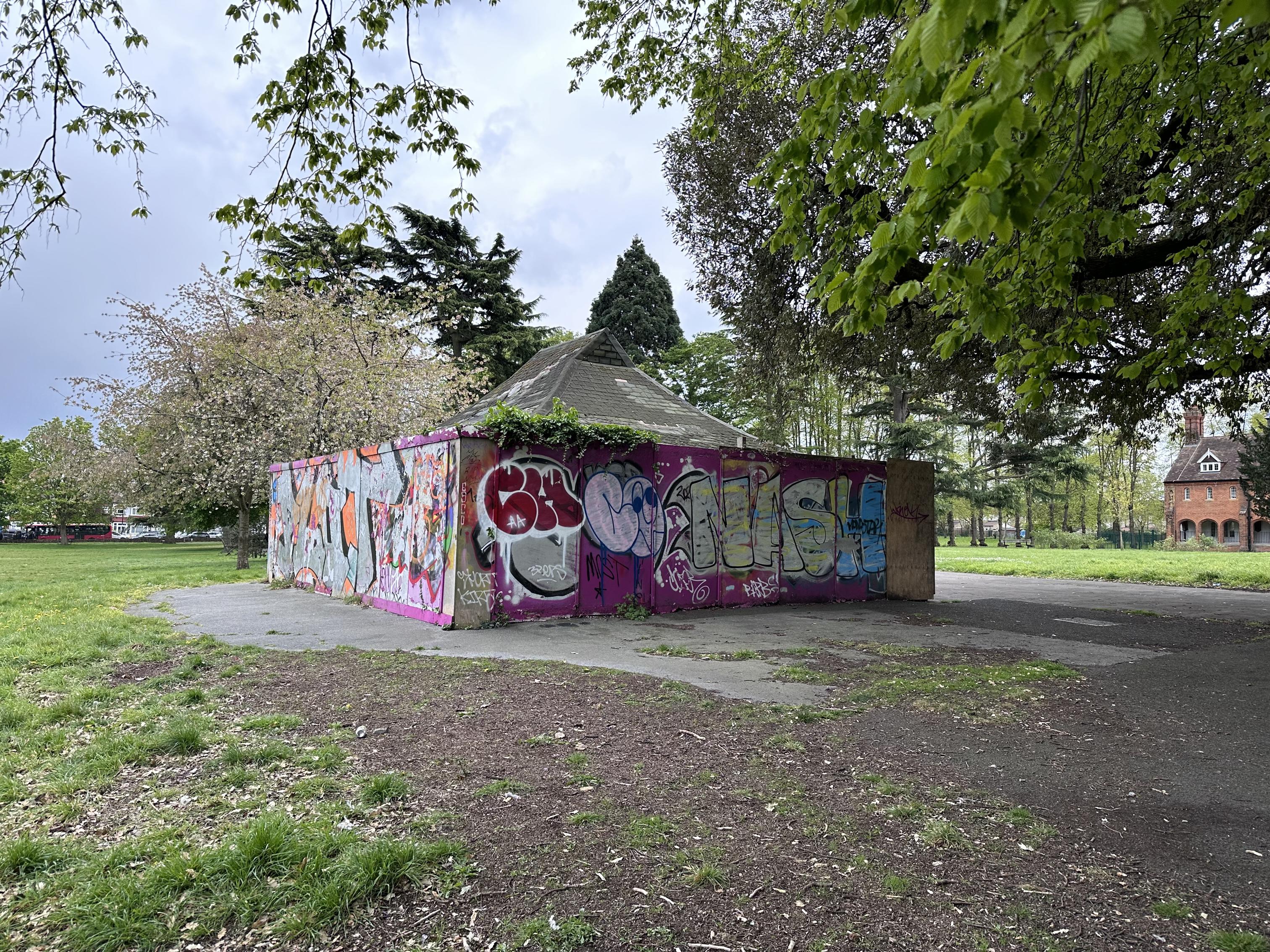 Graffiti-covered building in the middle of a green park