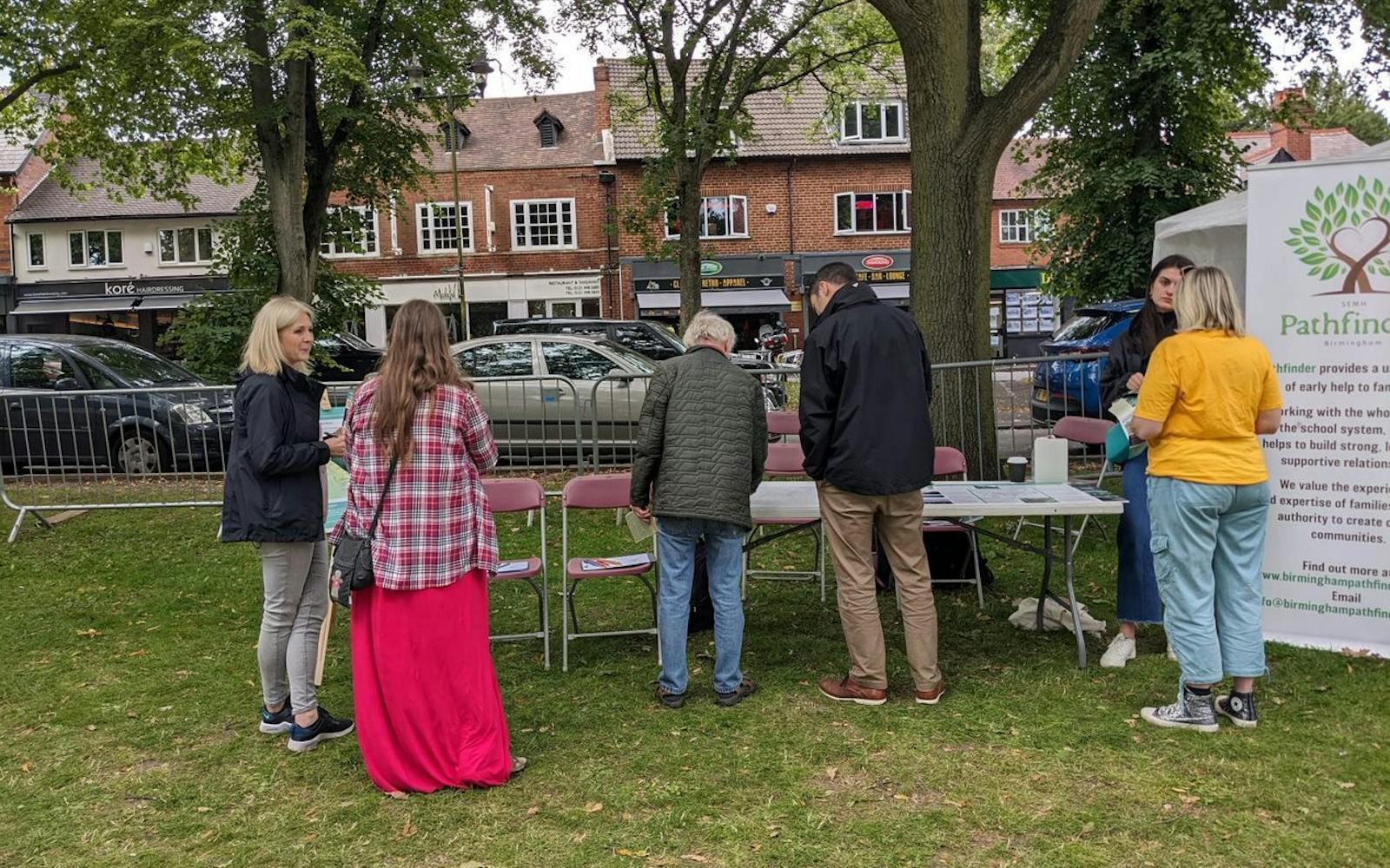 a group of people standing around tables and chairs