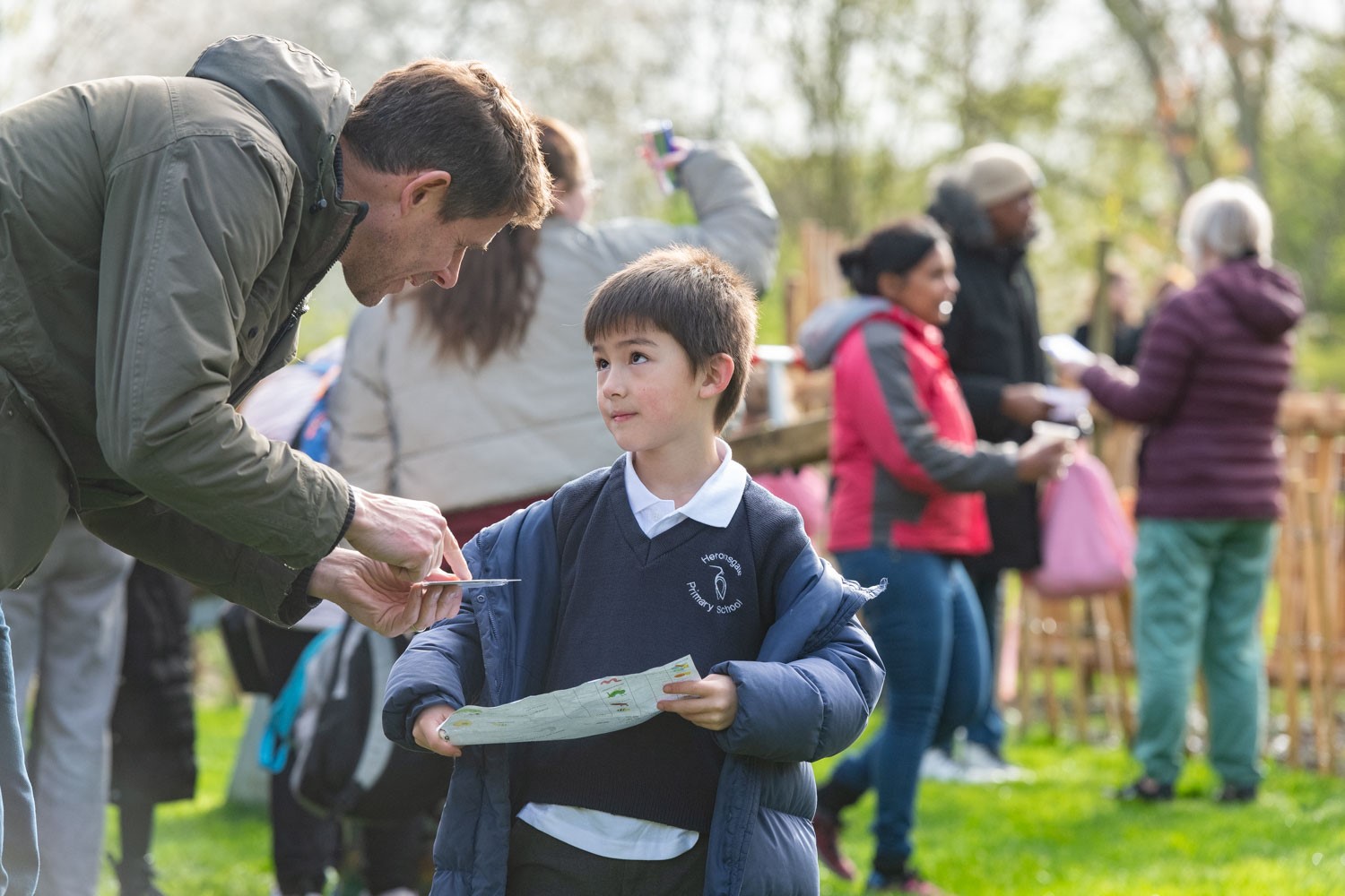 a man holding a paper and a child standing in a field