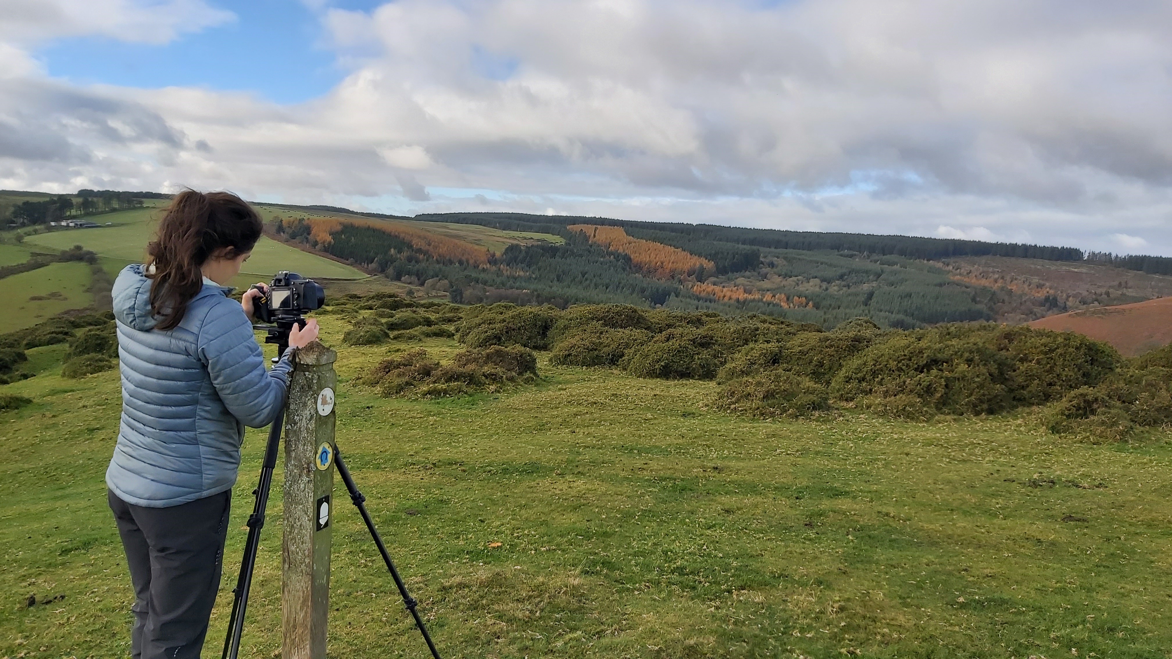 Countryside and hills. A person in the foreground with a camera on a tripod