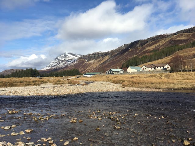 Some houses next to water with a snowy mountain in the background