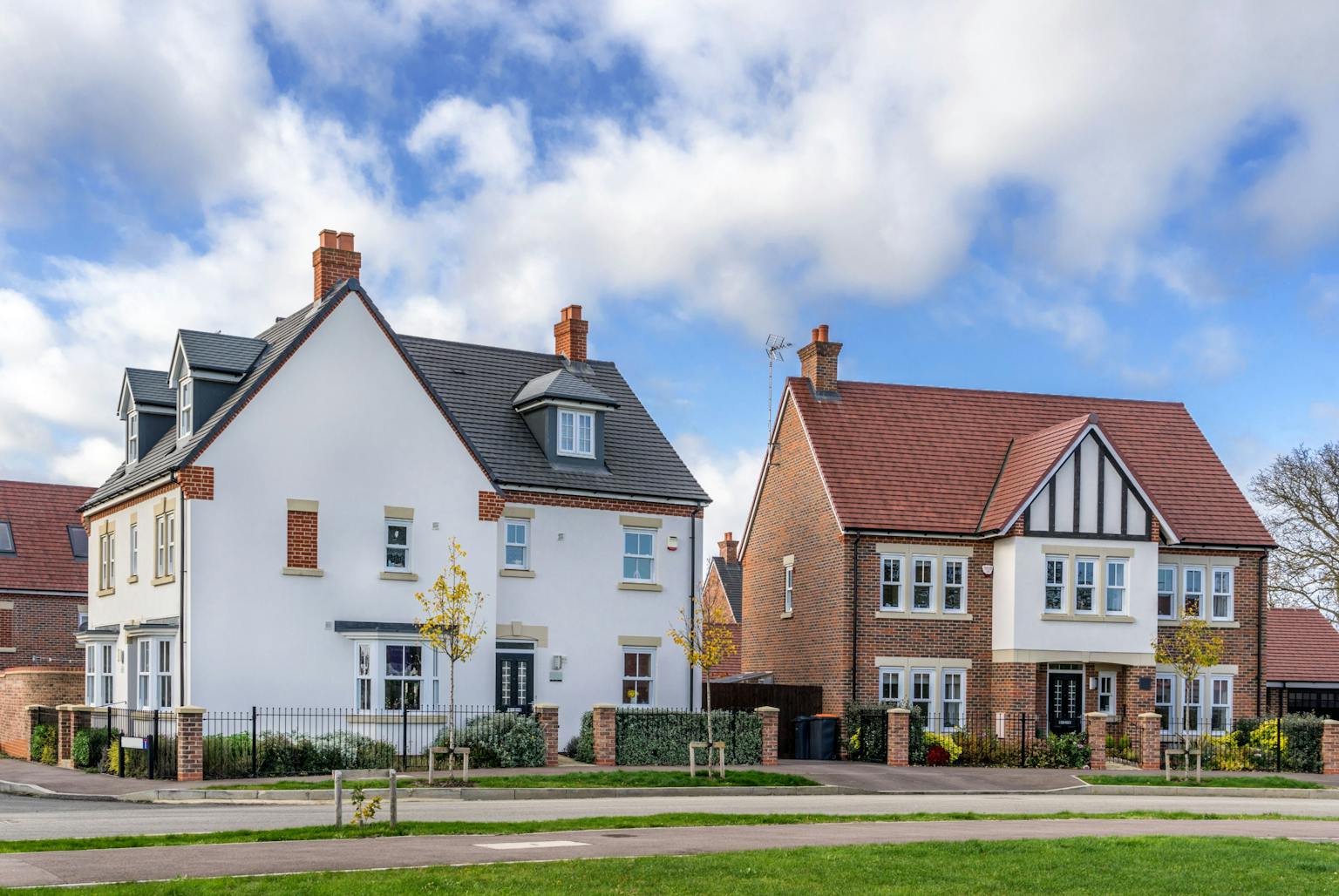 Two detached houses with similar exteriors stand side-by-side on a suburban street