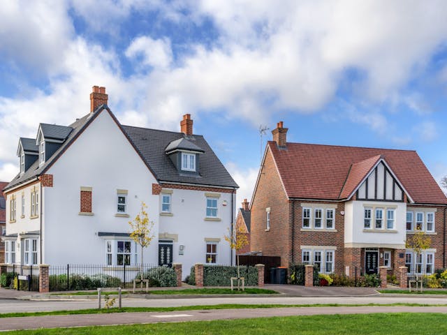 Two detached houses with similar exteriors stand side-by-side on a suburban street