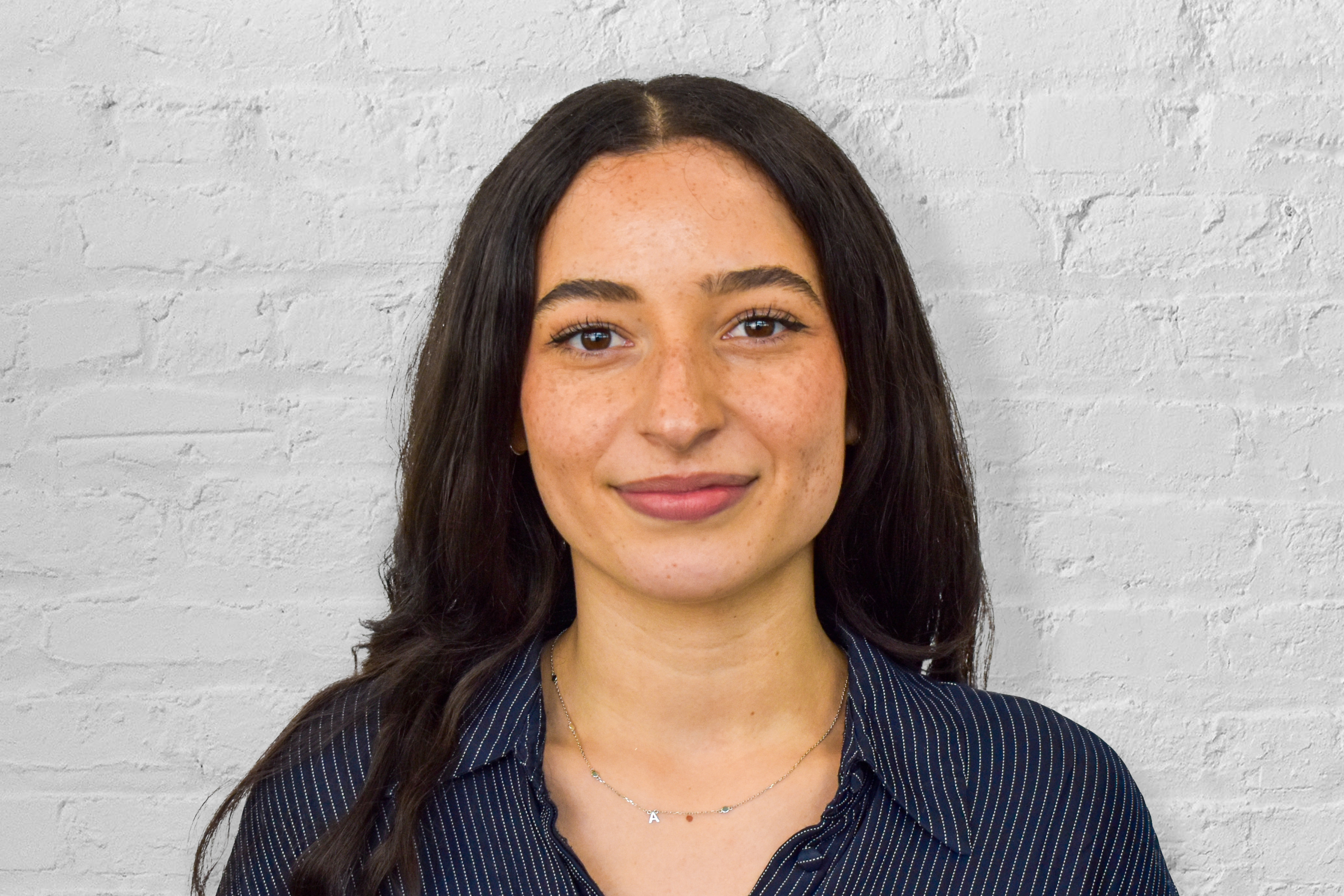 person smiling in front of brick wall