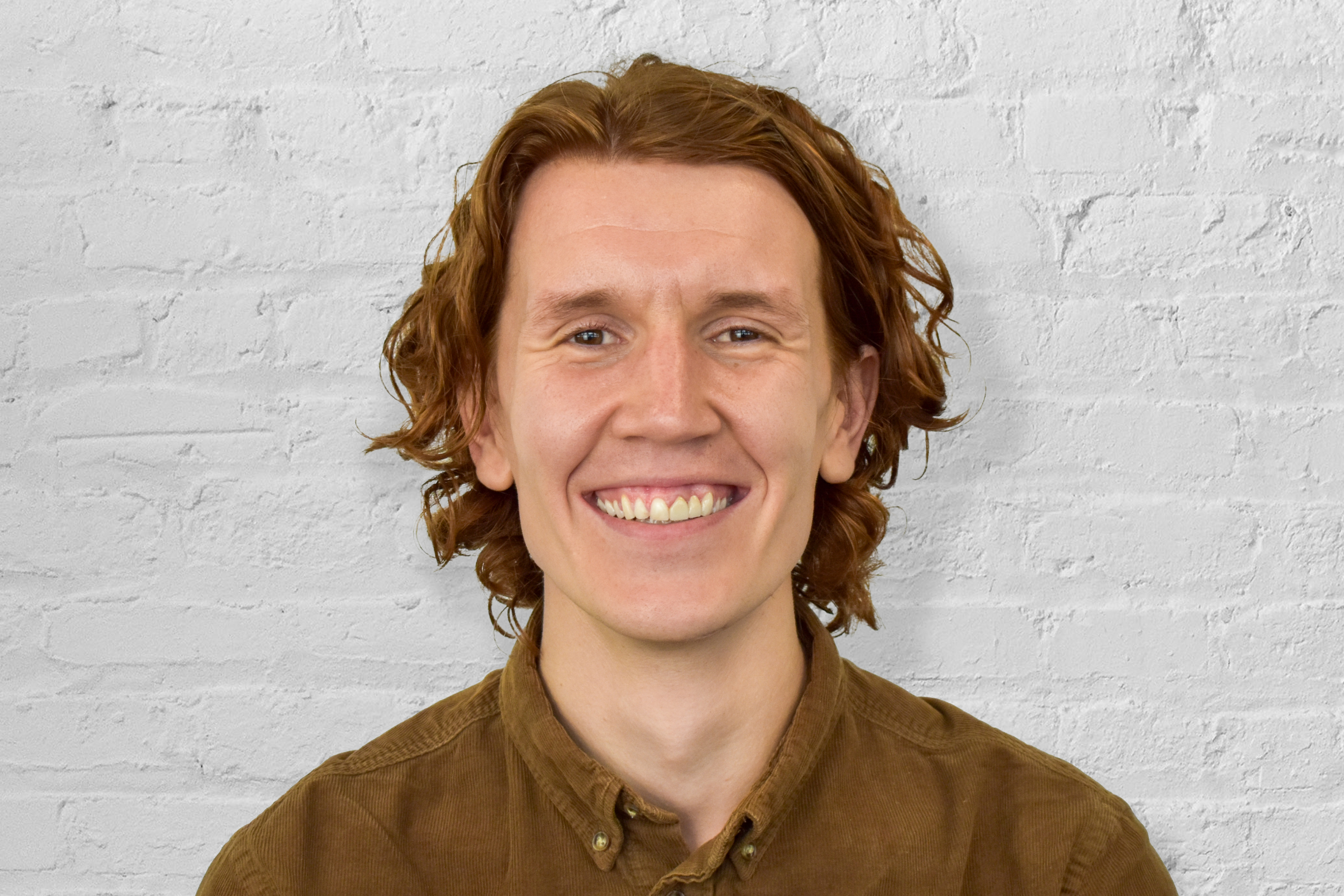 person smiling in front of brick wall