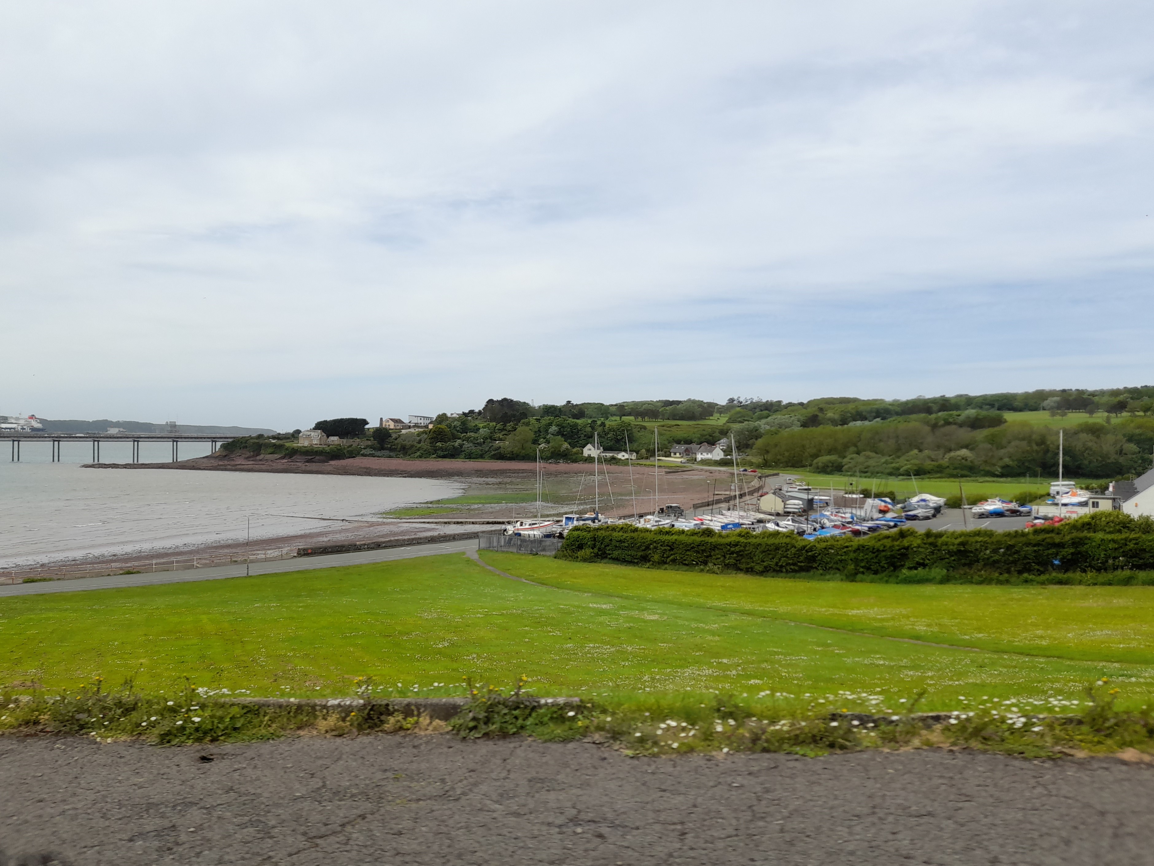 Harbor view with a long pier extending towards a suspension bridge in the distance