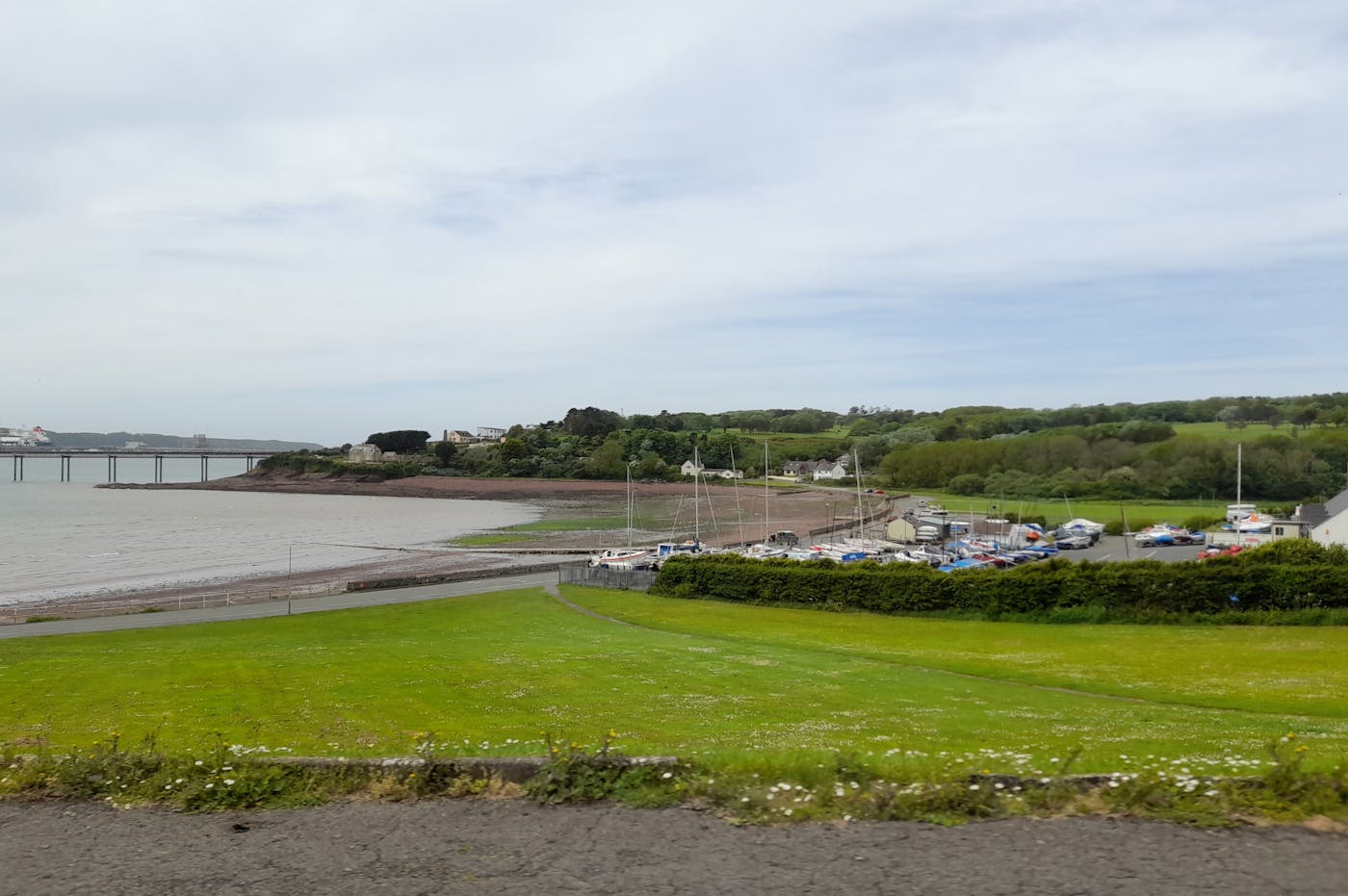 Harbor view with a long pier extending towards a suspension bridge in the distance
