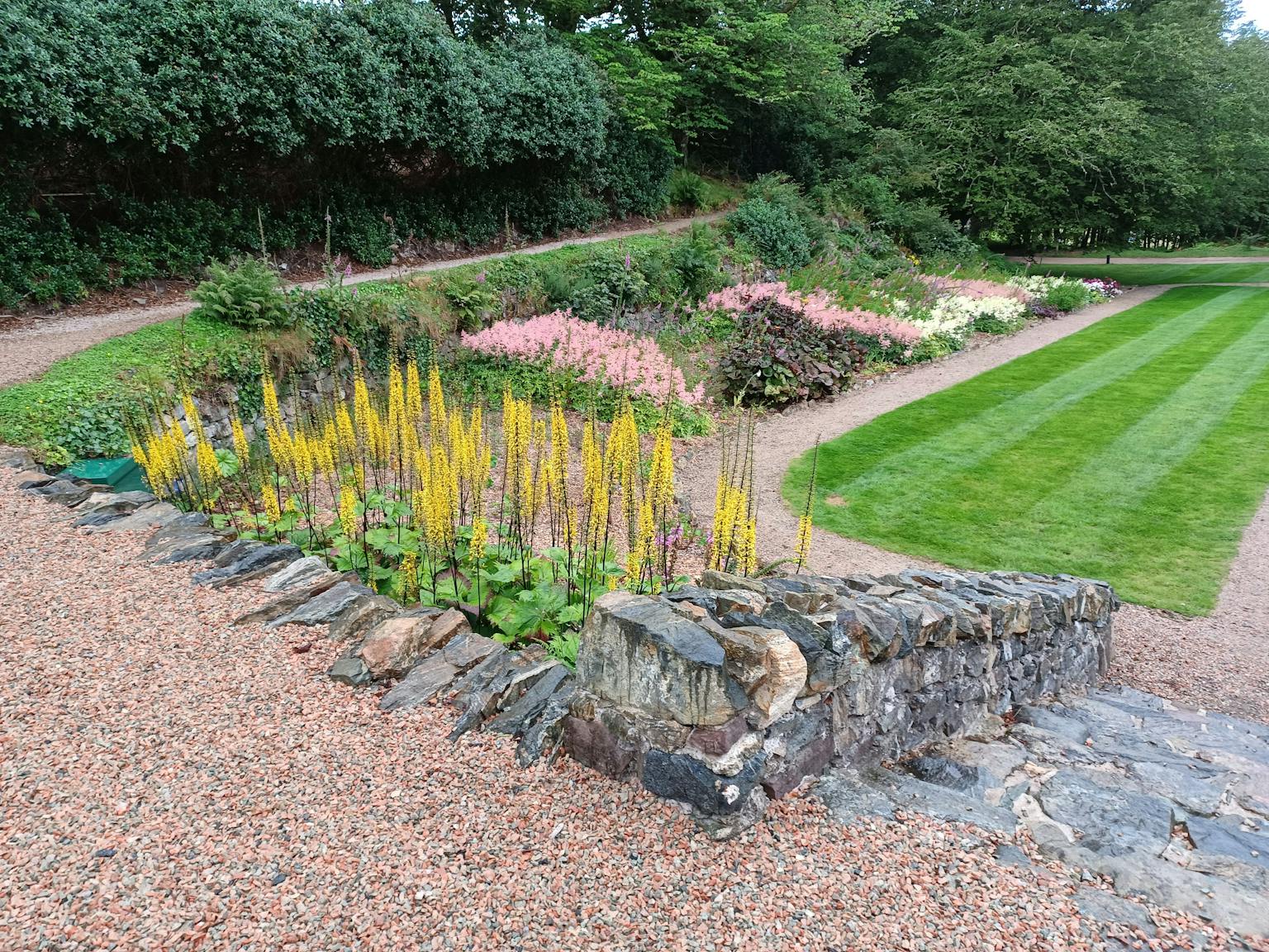 A garden with flowers and a lawn next to a path