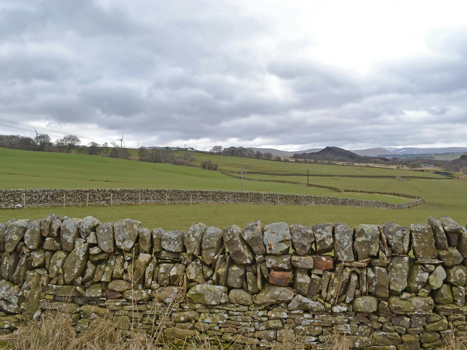 Countryside - fields and mountains in the distance. Dry stone wall in the foreground