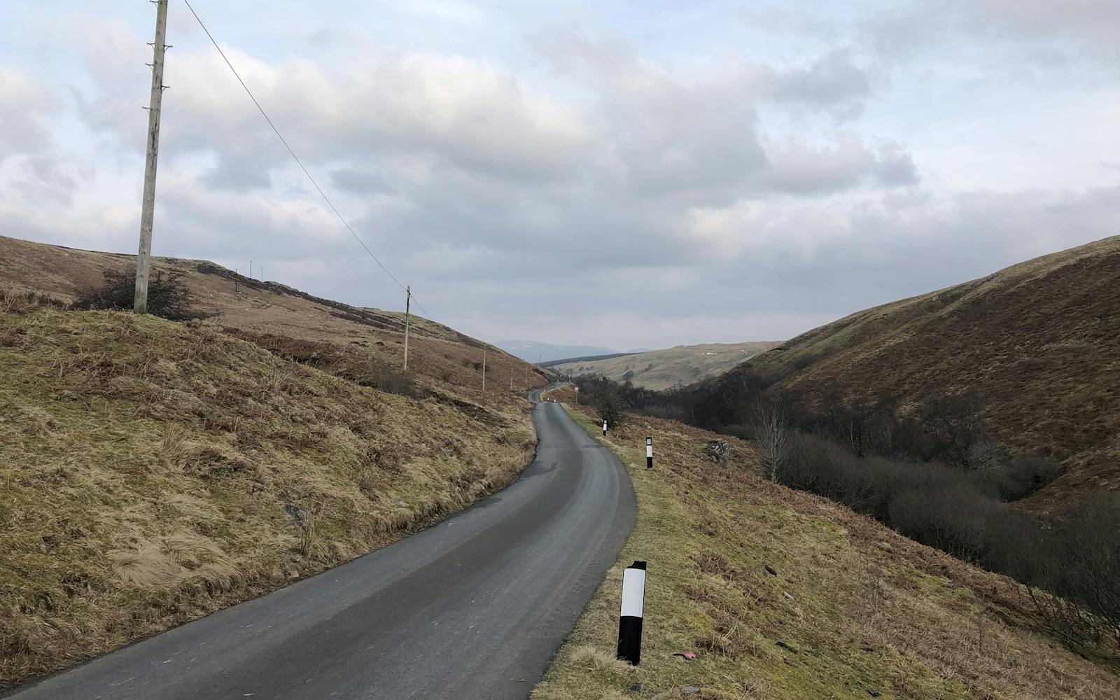 A road going through the countryside with electricity lines running alongside