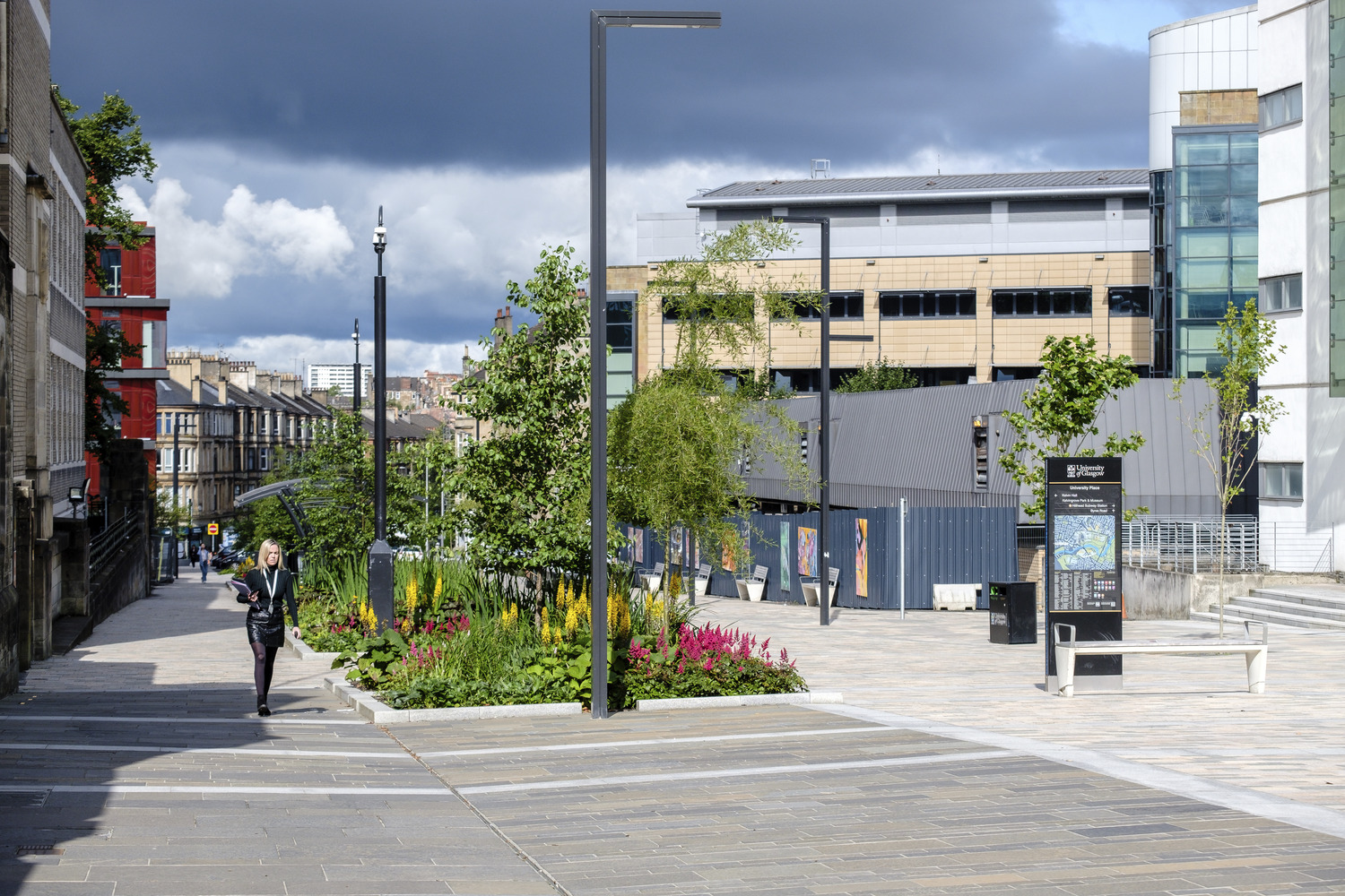Walkway between university building with lampposts and greenery