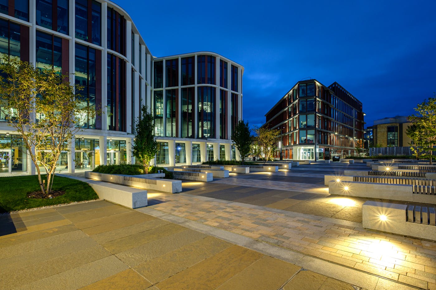 A night view of the University of Glasgow's tall, modern building with many windows. The building has a glass facade which reflects the sky and surrounding buildings