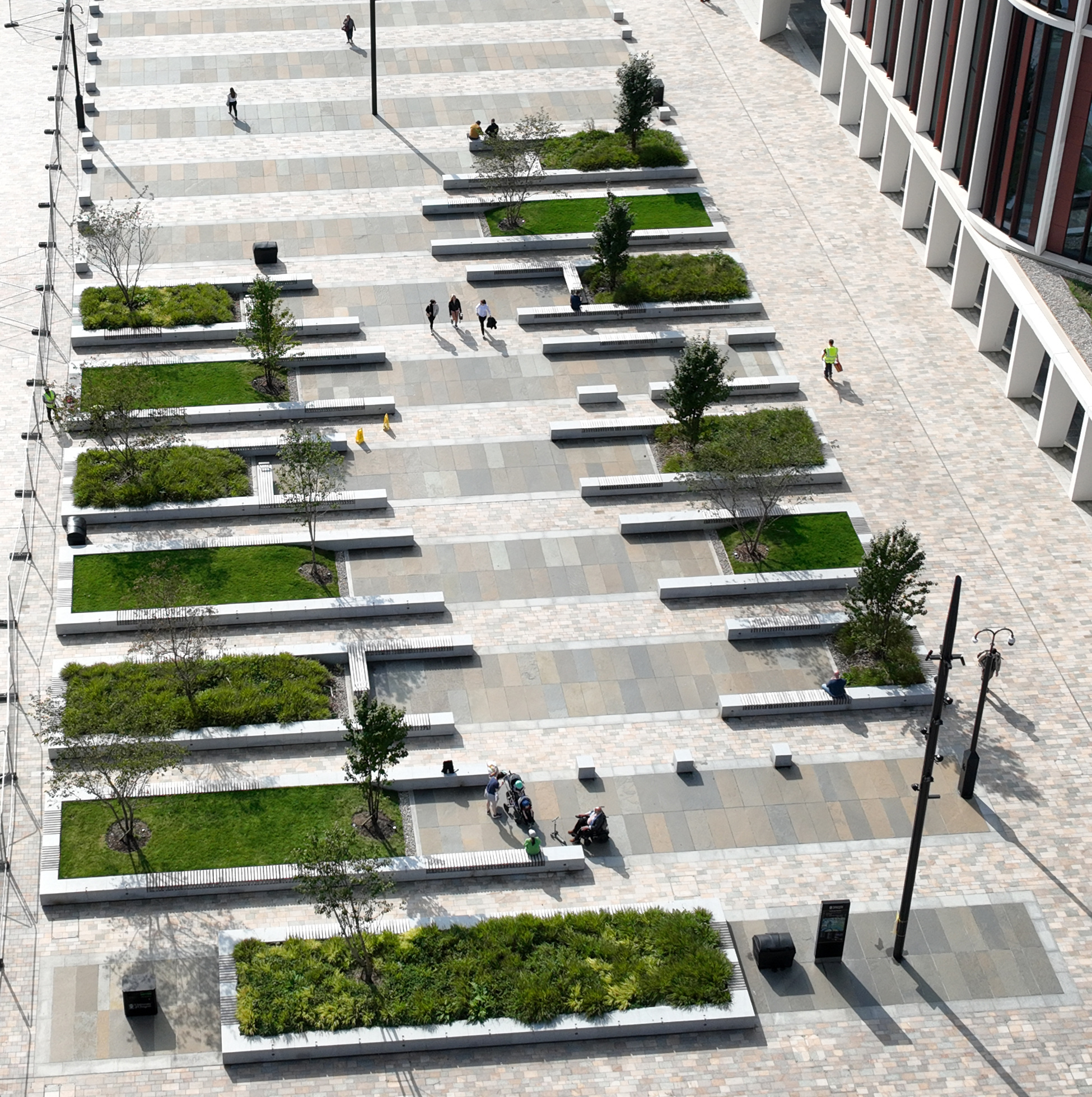 An aerial view of a plaza with modern benches and shade trees