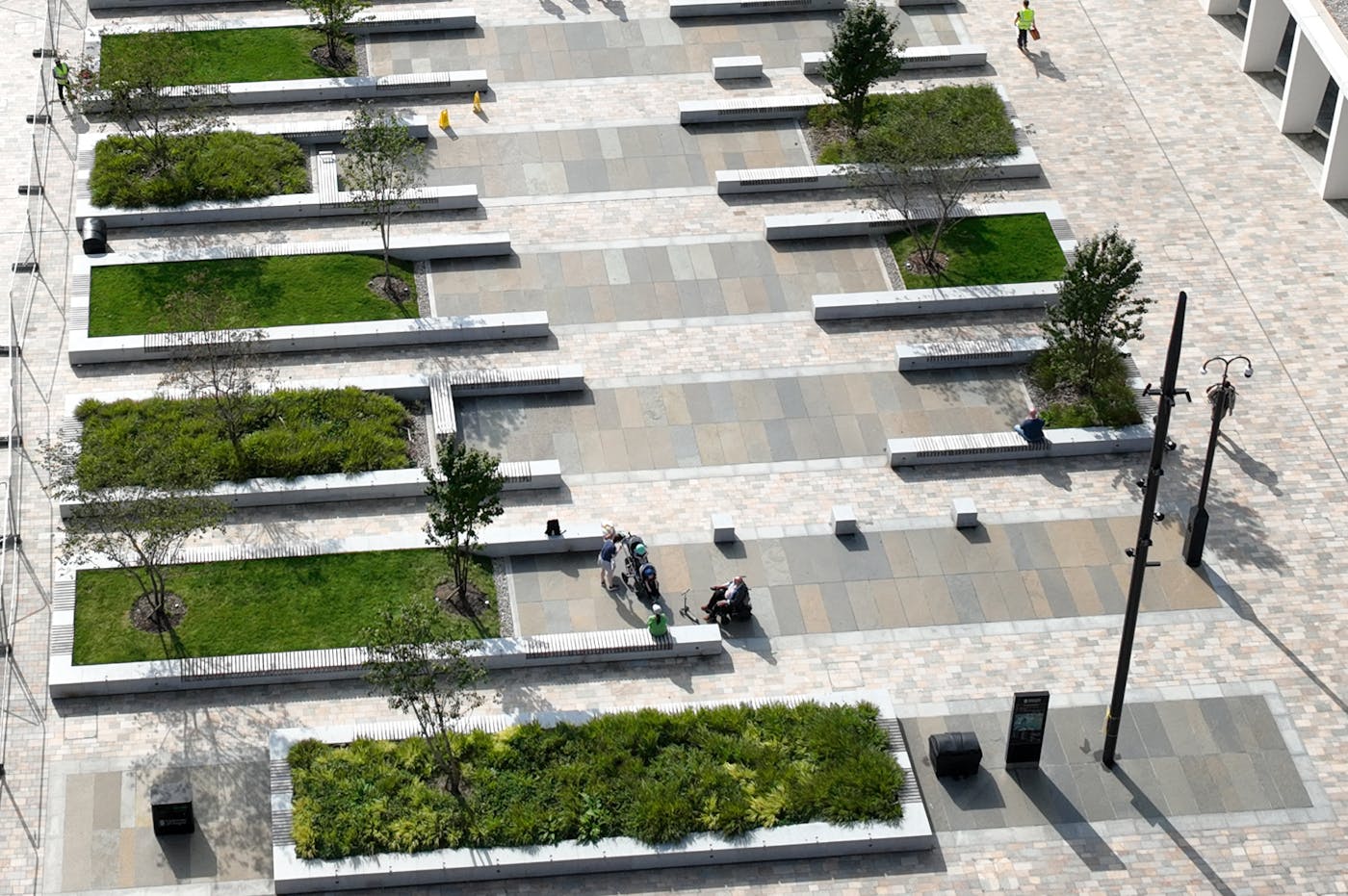 An aerial view of a plaza with modern benches and shade trees