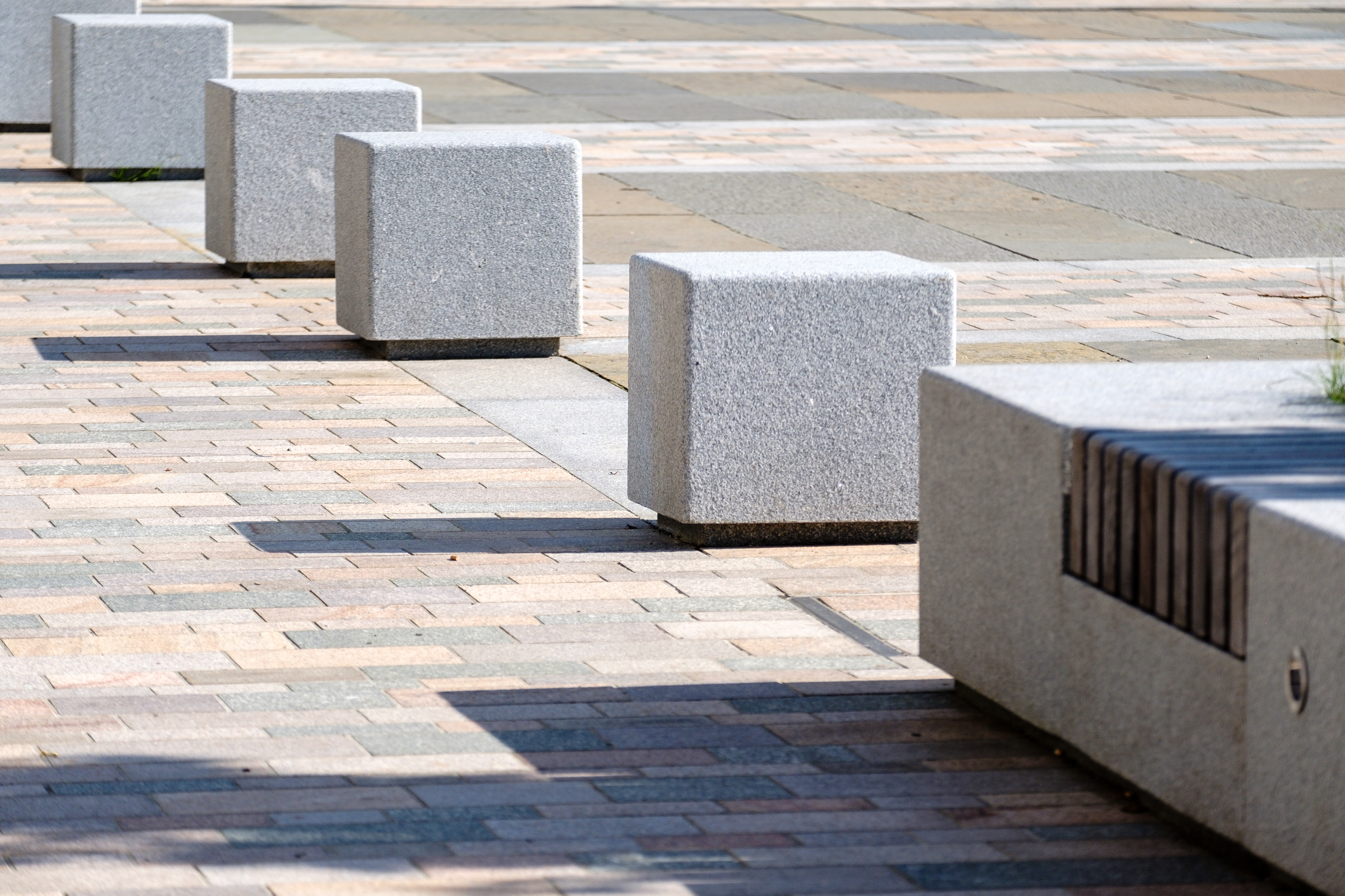 A row of interlocking concrete bollards on a brick pavement