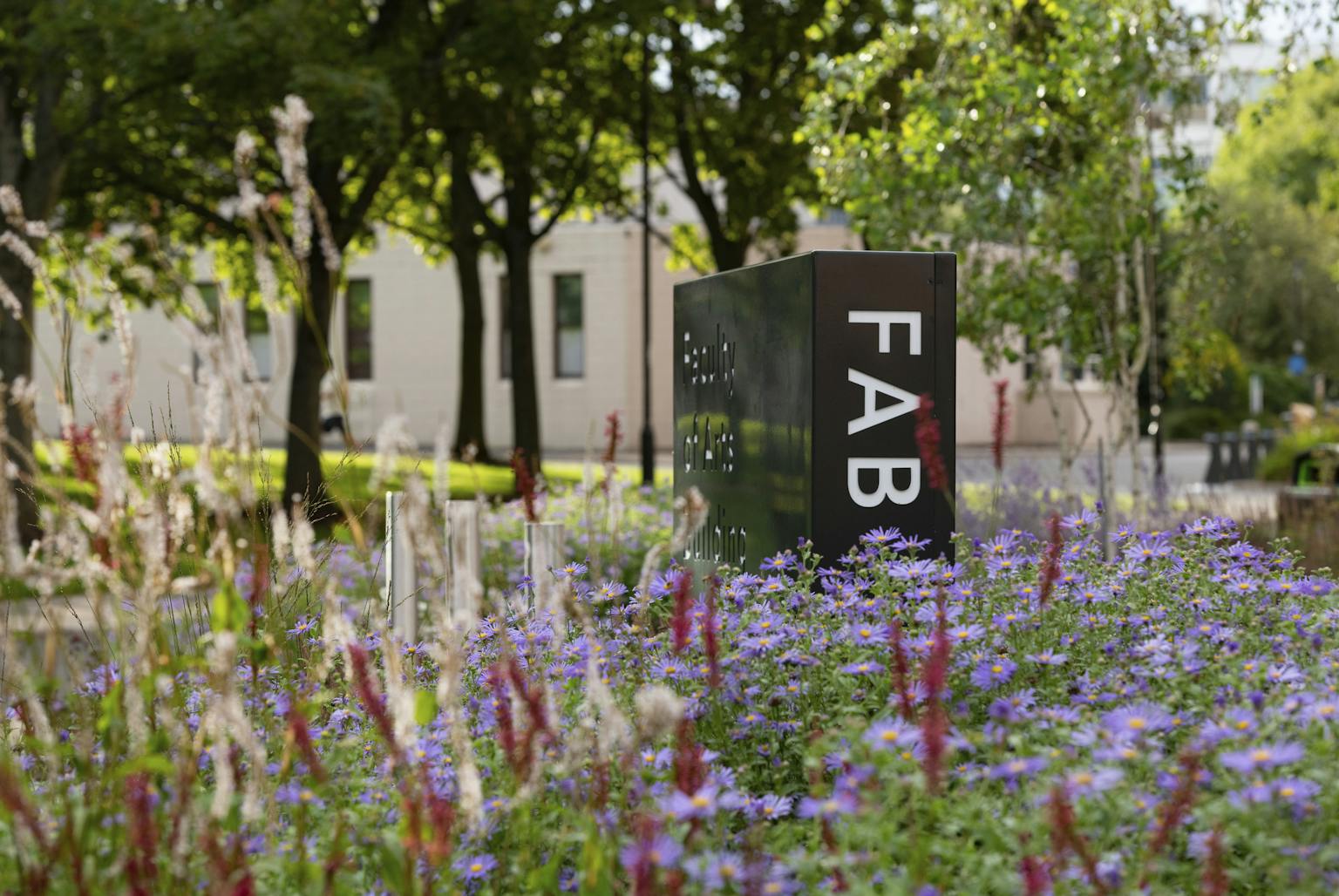 A black and white sign with the text "FAB" standing in a field of purple flowers