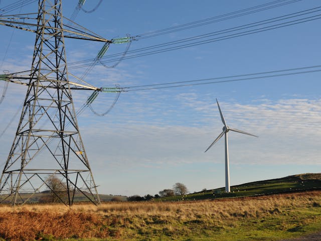 An electricity pylon and wind turbine in open countryside
