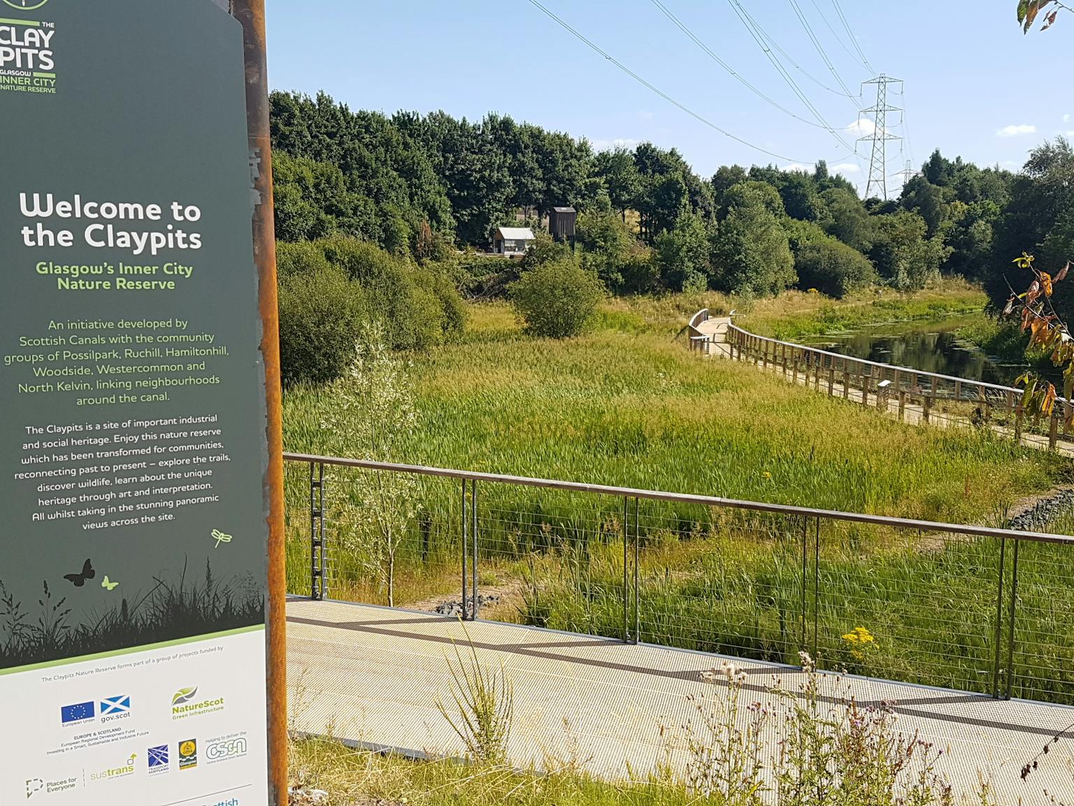 A sign in the foreground with greenery and trees