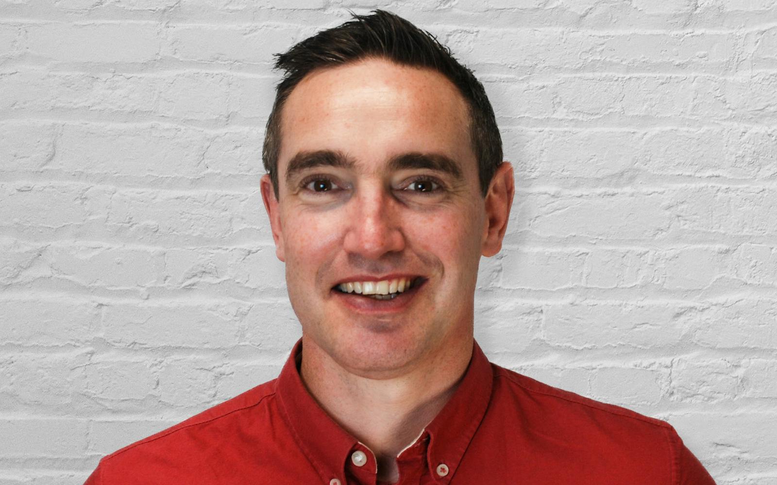 Headshot of a person in front of a white brick wall