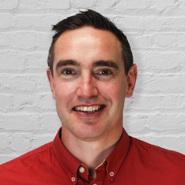 Headshot of a person in front of a white brick wall