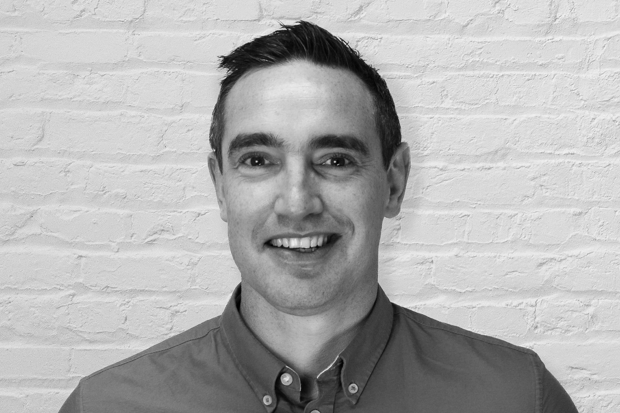Headshot of a person in front of a white brick wall
