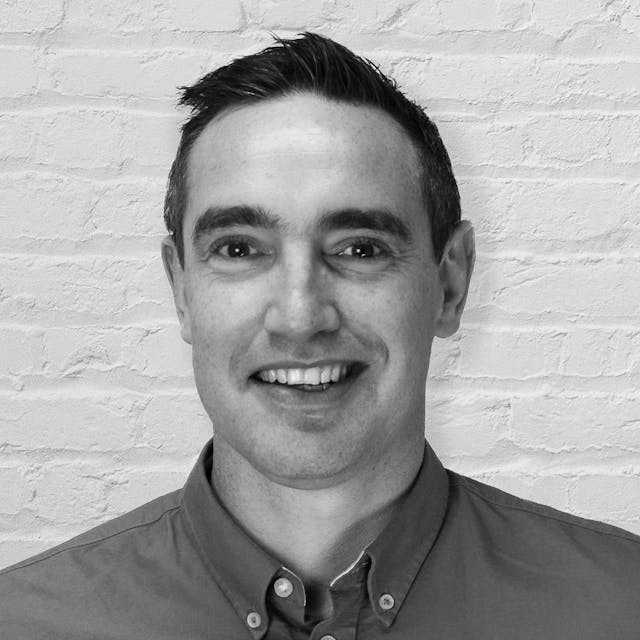 Headshot of a person in front of a white brick wall
