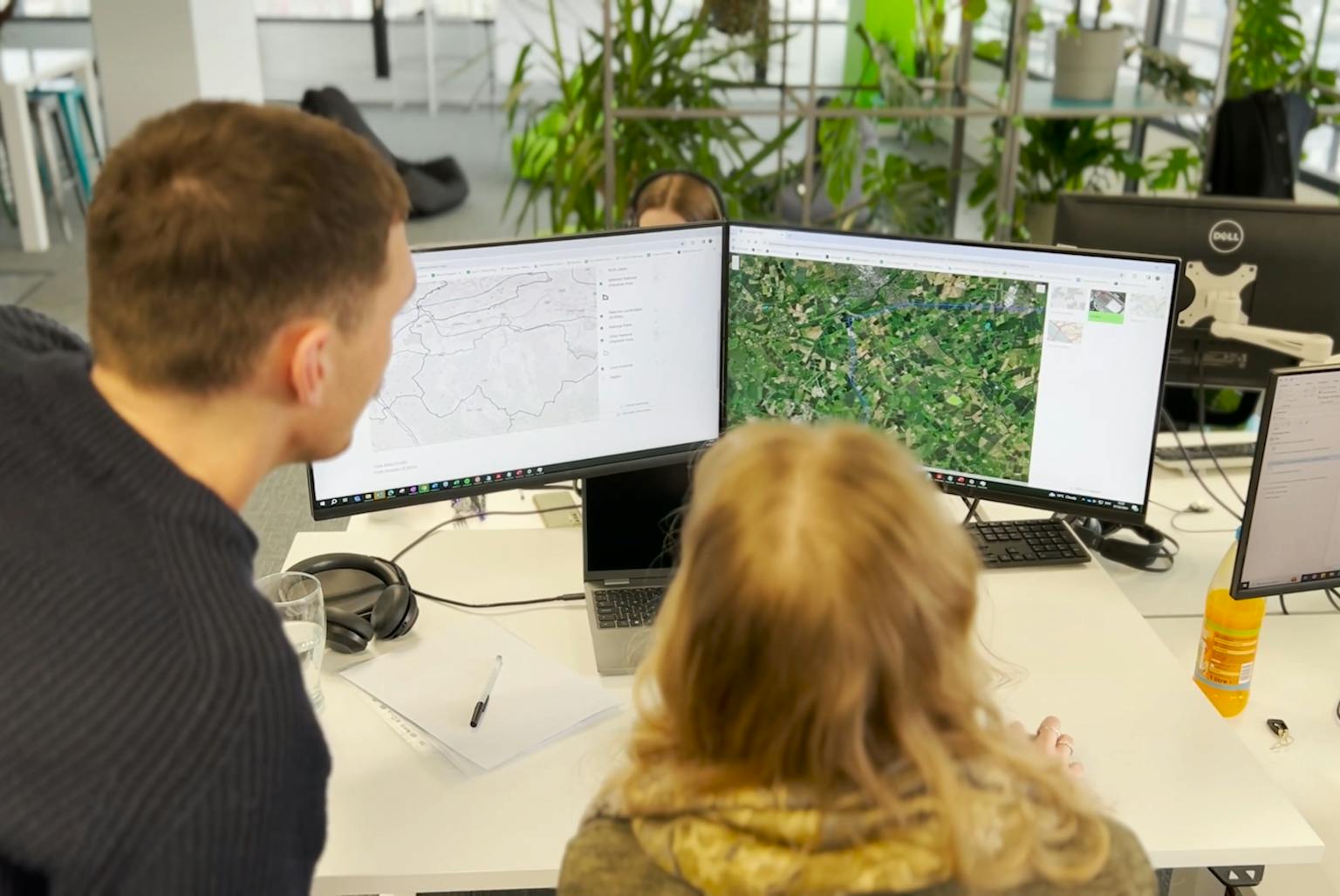A person sat in front of a PC screen looking at a green aerial photo