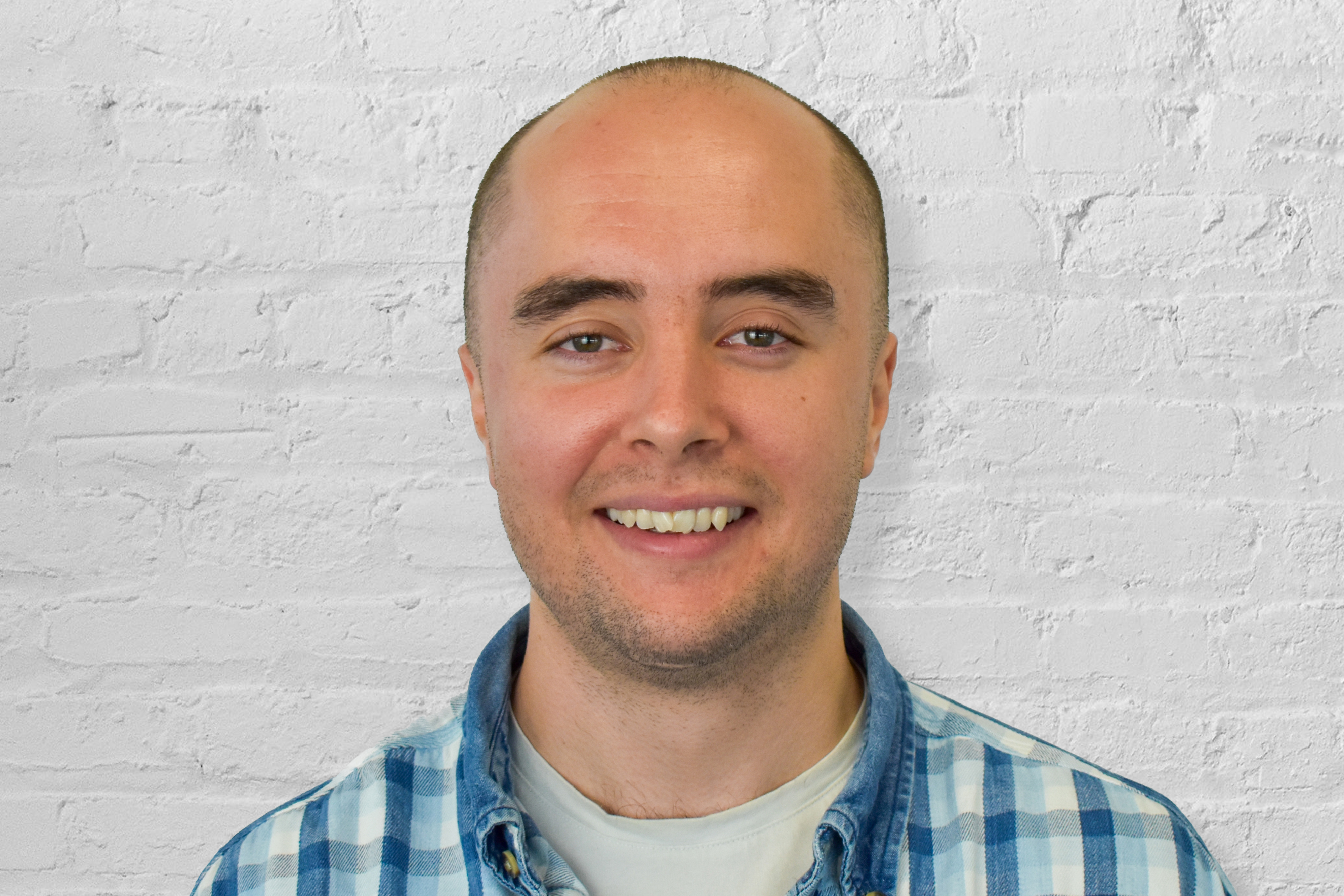 Headshot of a person in front of a white brick wall