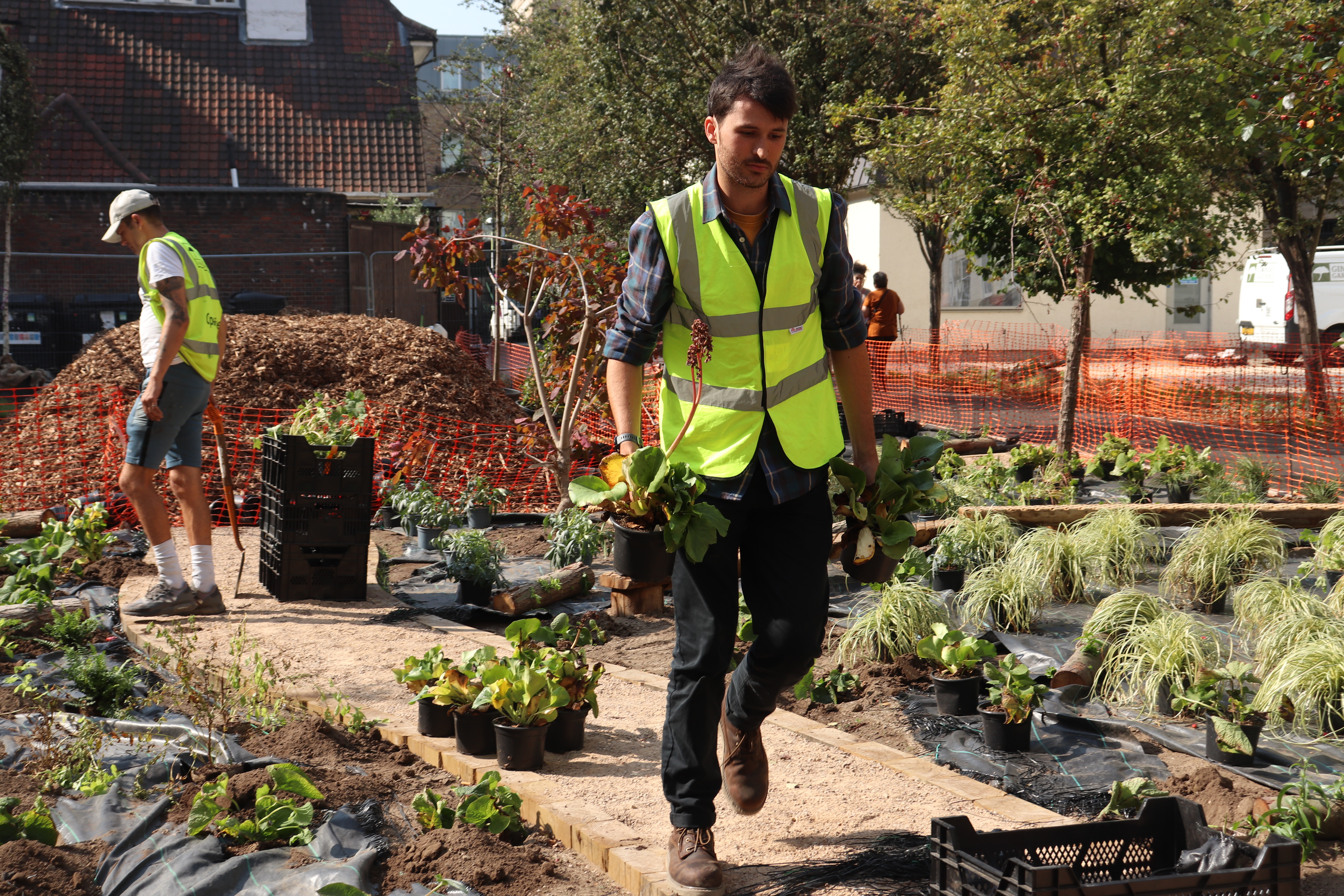 A man in a high-visibility vest working in an urban garden