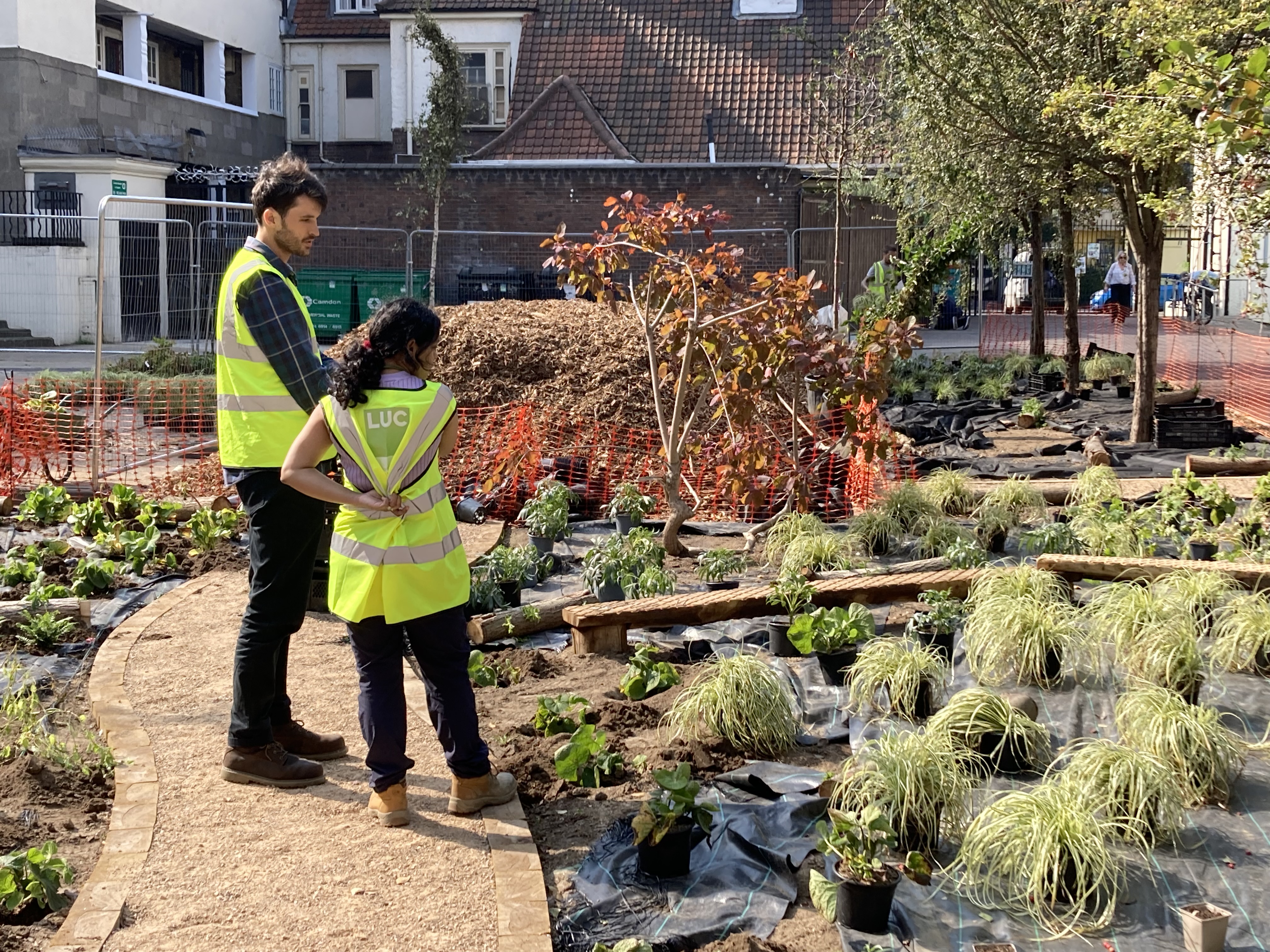 Two people in high-visibility vests working in an urban garden